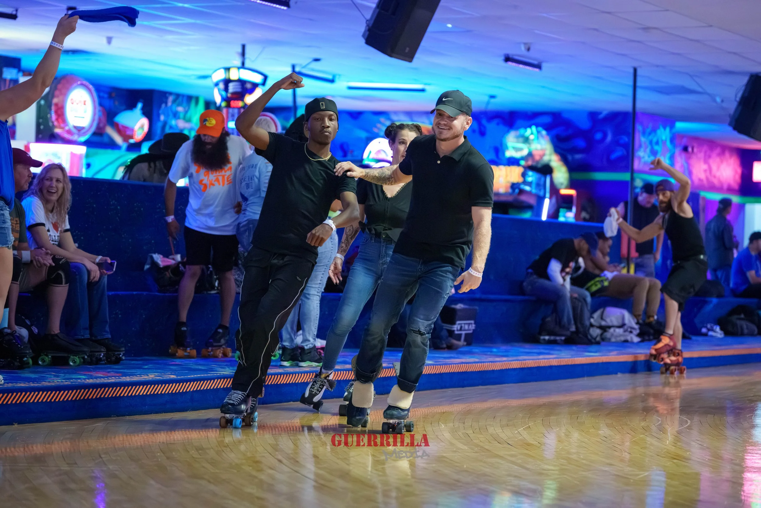 People roller skating and dancing at an indoor roller rink with neon lights and spectators watching.