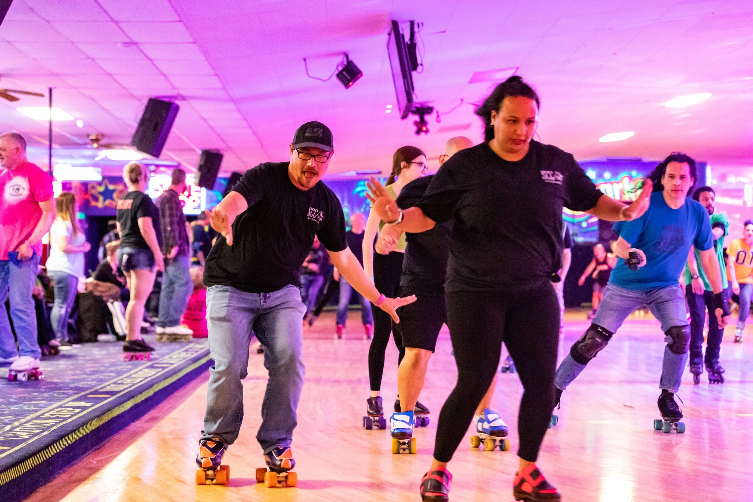 People roller skating at an indoor skating rink with colorful neon lights.