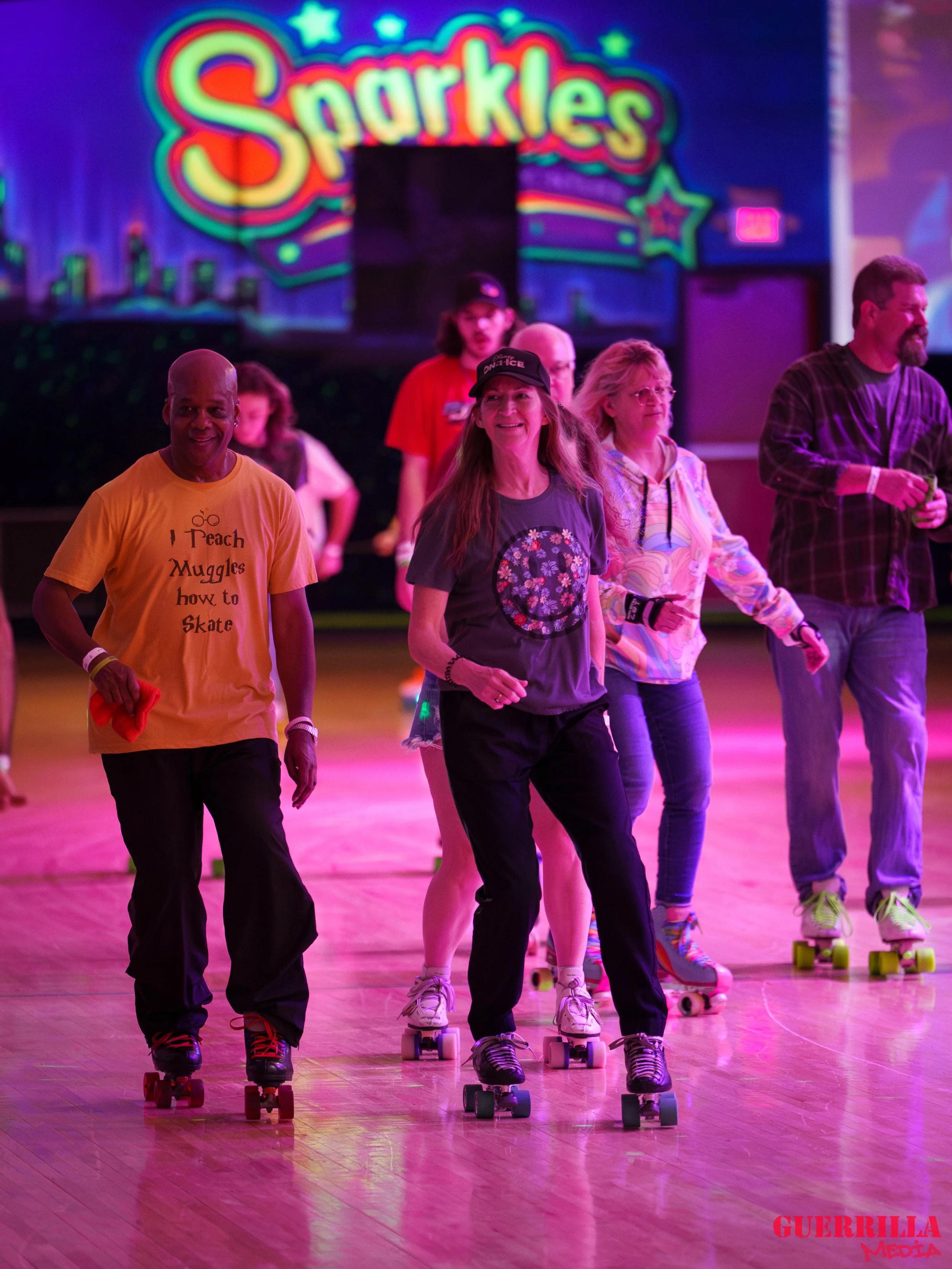 People roller skating in a brightly lit indoor rink with colorful lights and a 'Sparkles' sign in the background.