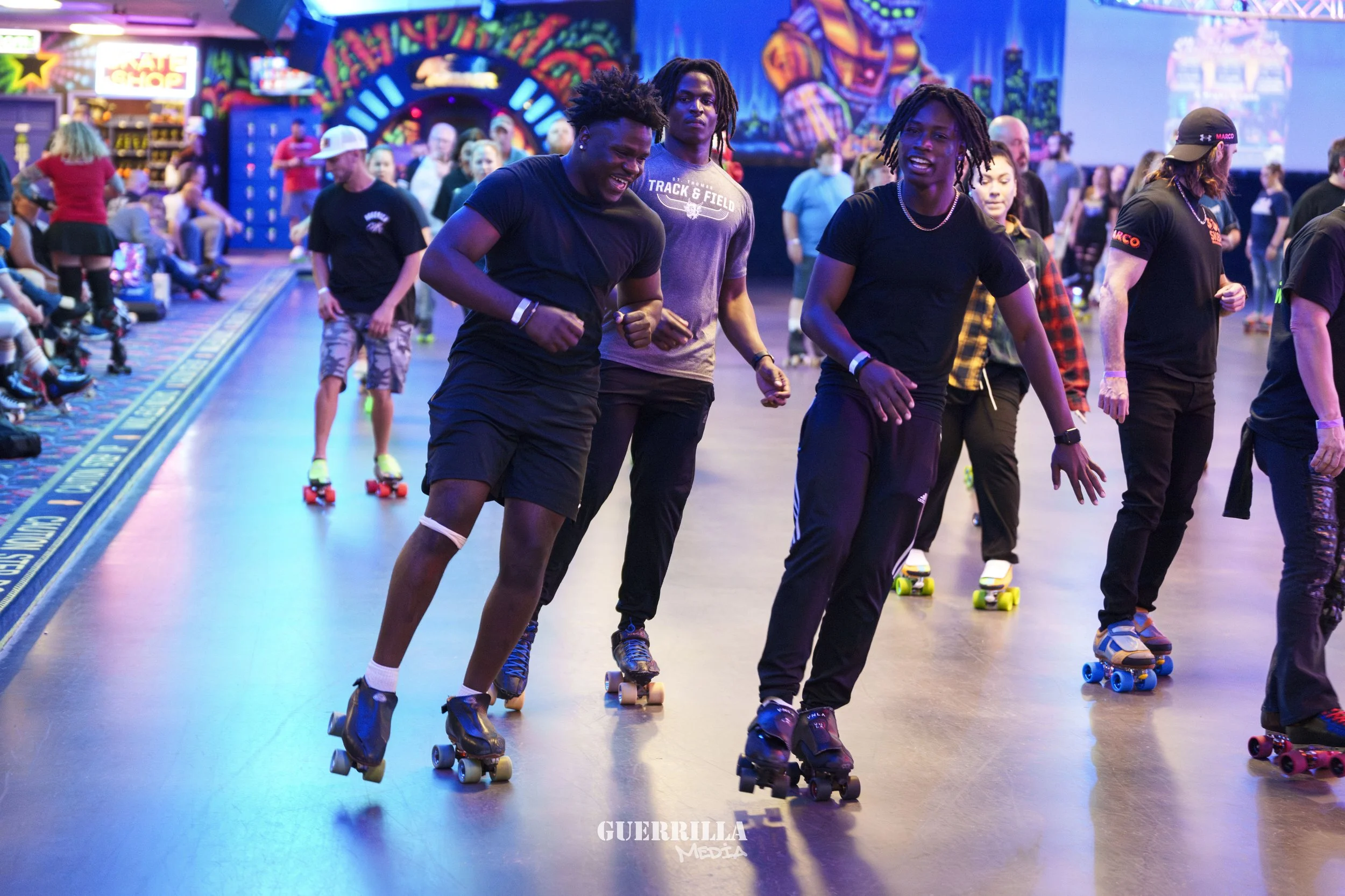 People roller skating inside an arcade with colorful neon lights and decorations.