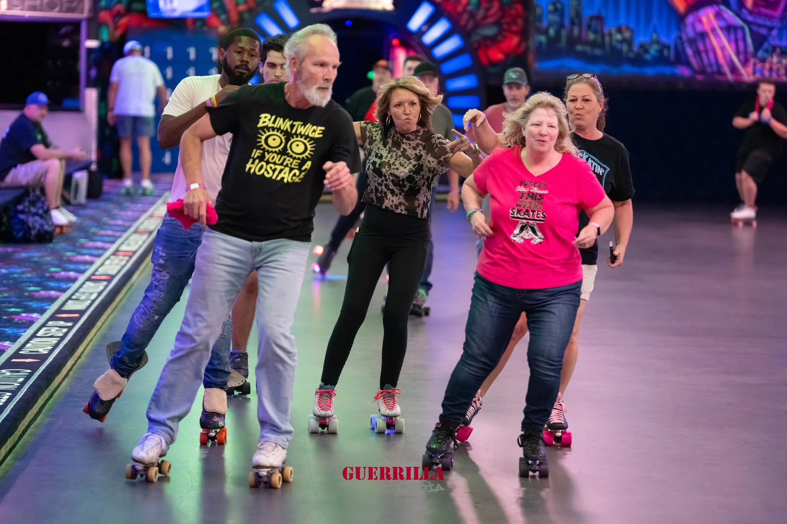 A group of people roller skating in an indoor roller rink with neon lights and colorful decorations.