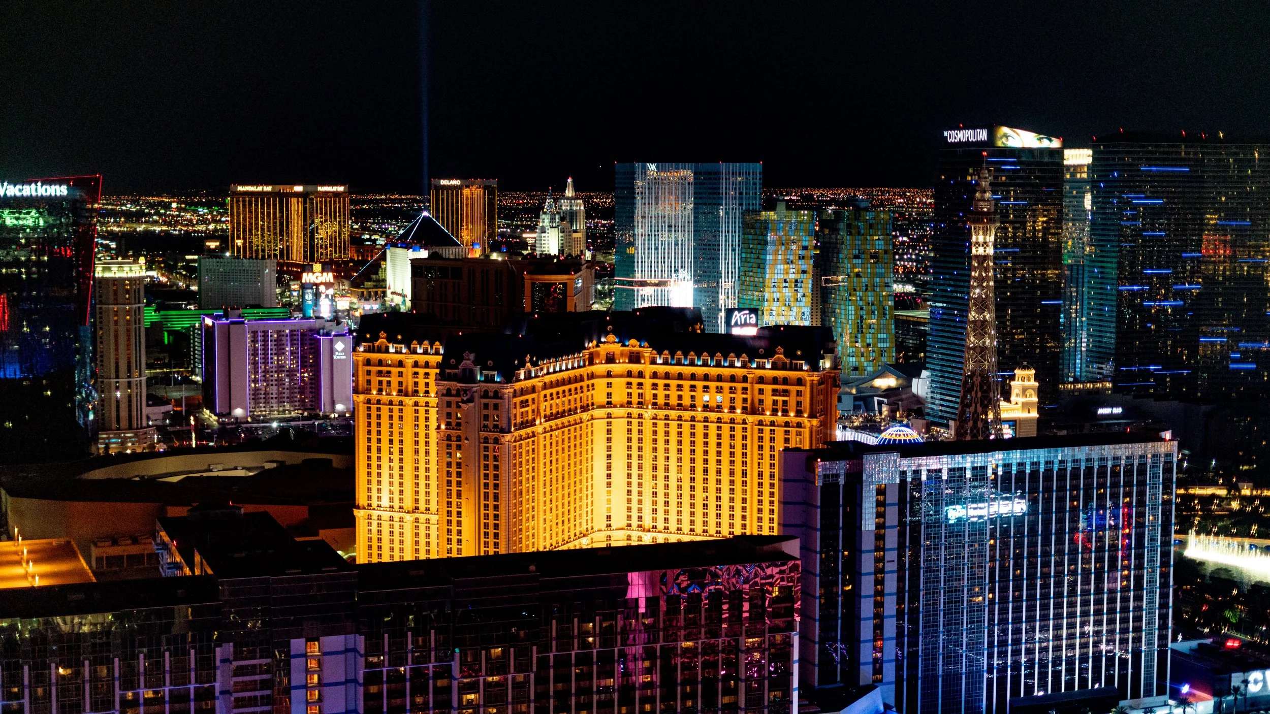 Nighttime cityscape of Las Vegas with brightly lit hotels and skyscrapers.