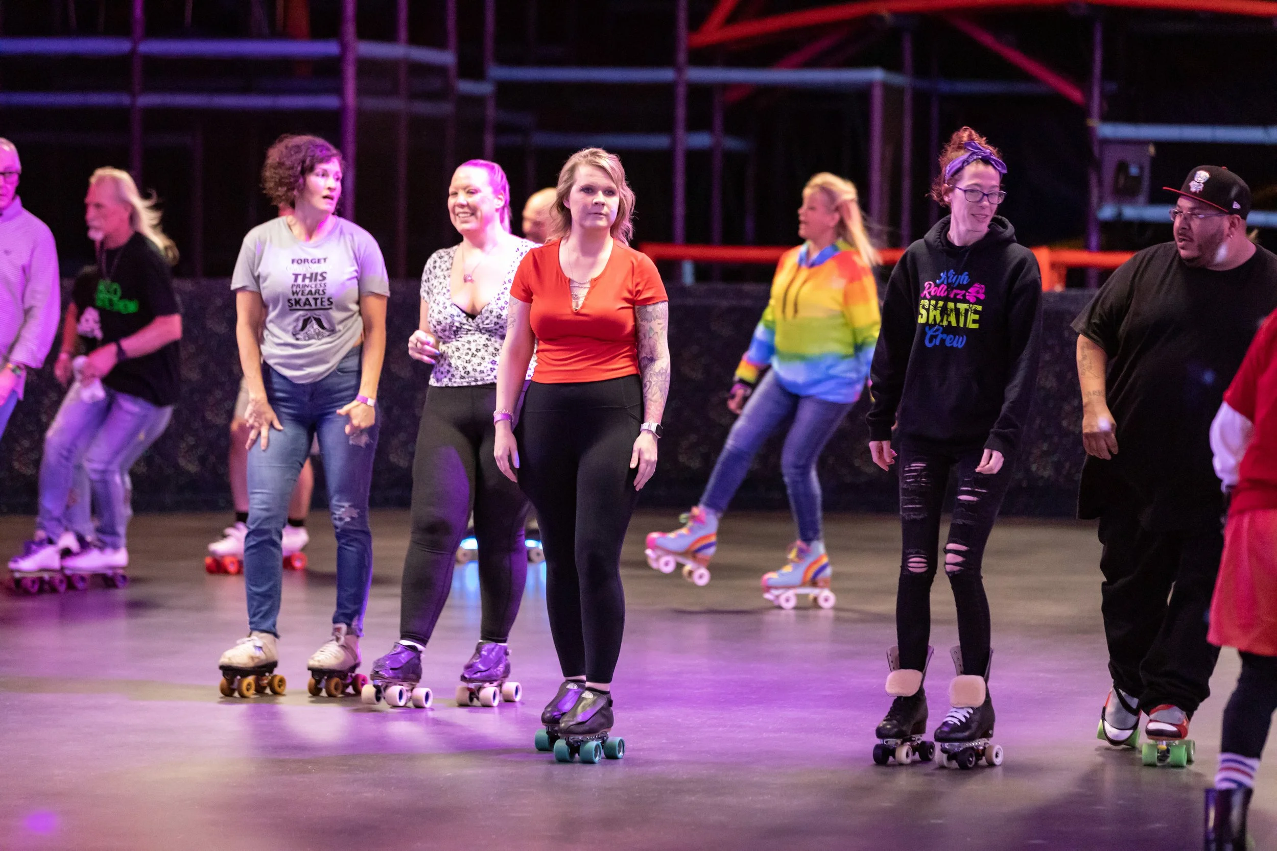 People roller skating together indoors at a skating rink, some smiling and interacting.