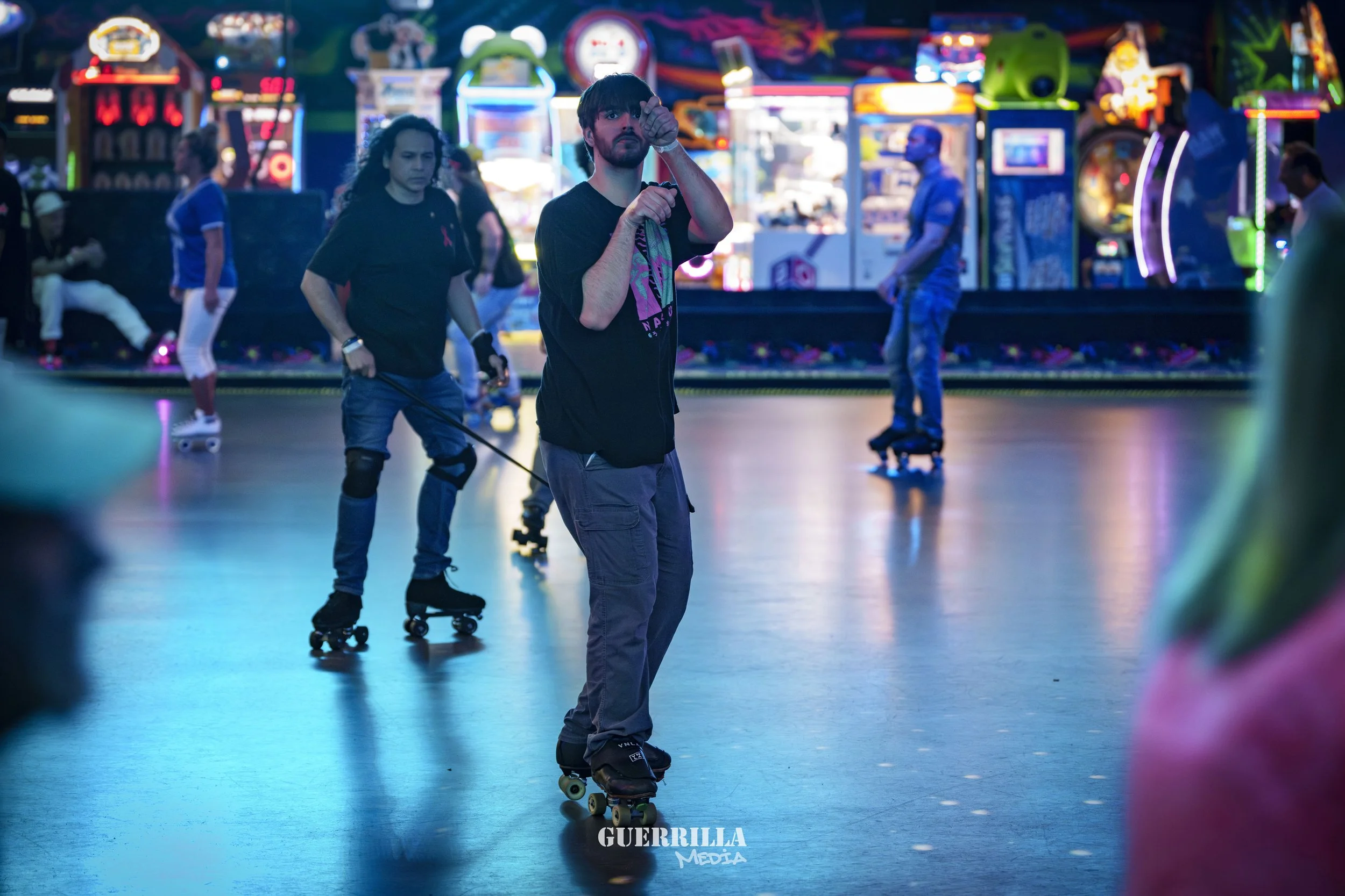 People roller skating at an indoor roller rink with colorful neon lights and arcade games in the background.