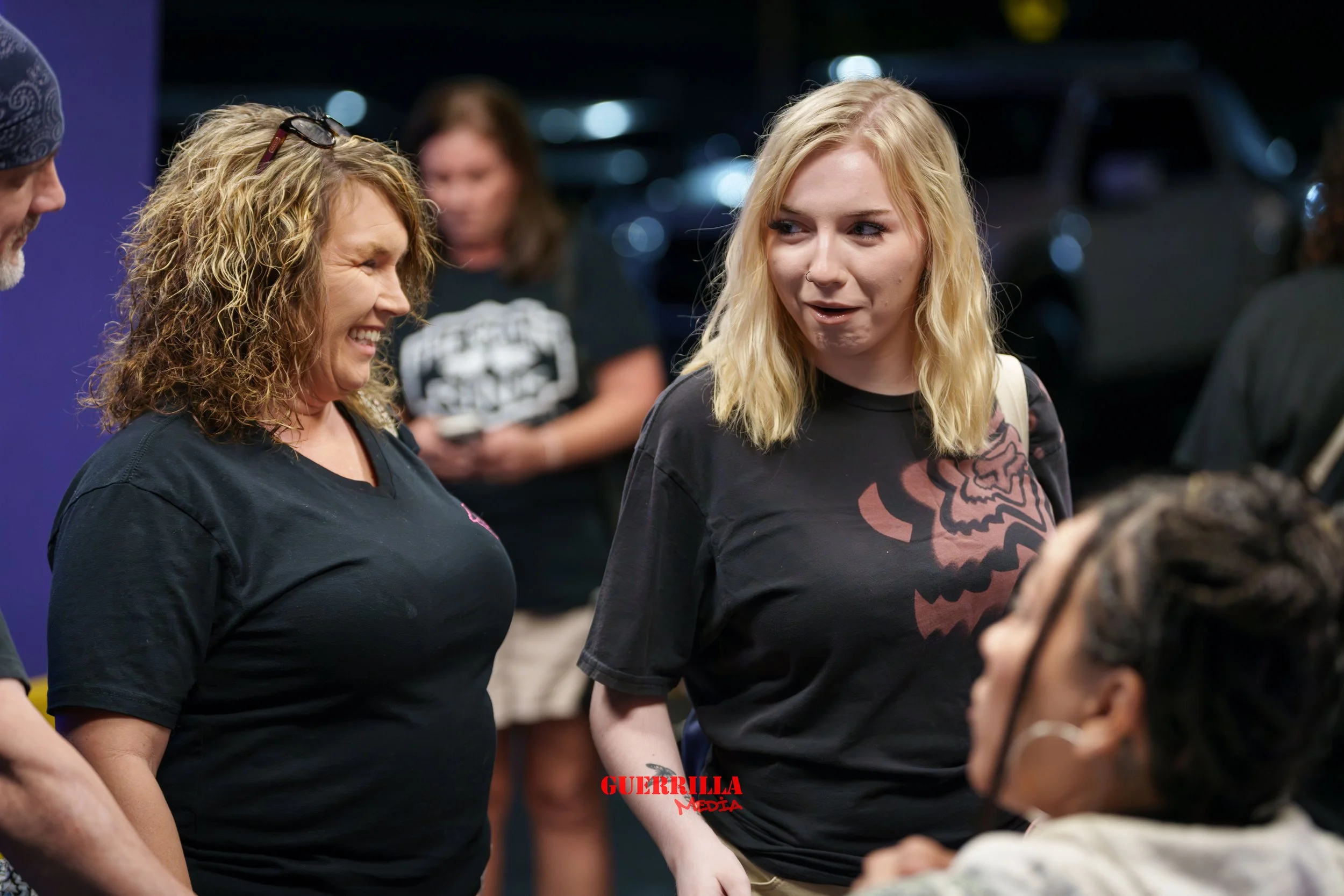 Group of people engaging in conversation at an outdoor event at night.