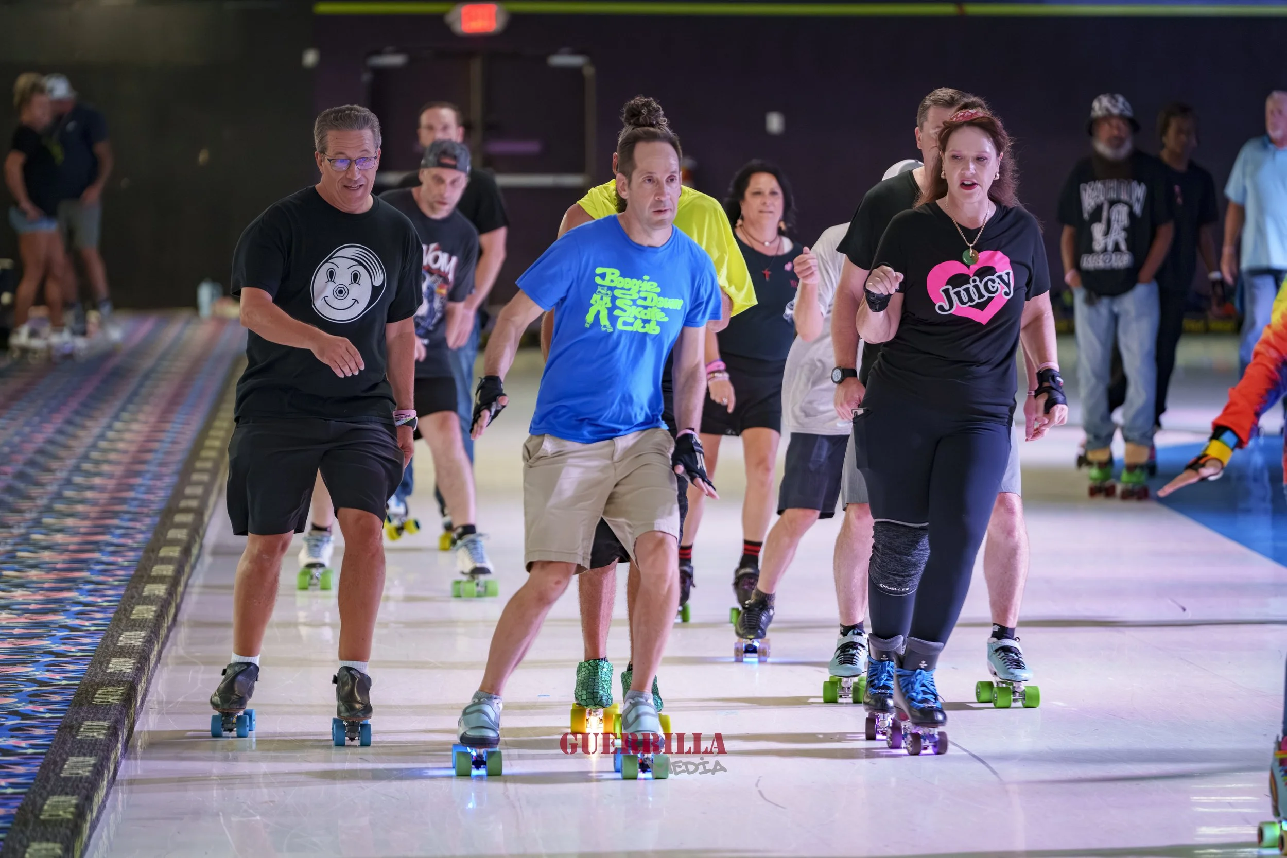 Group of people roller skating indoors, wearing casual and vintage-style clothing, with some smiling and enjoying the activity.