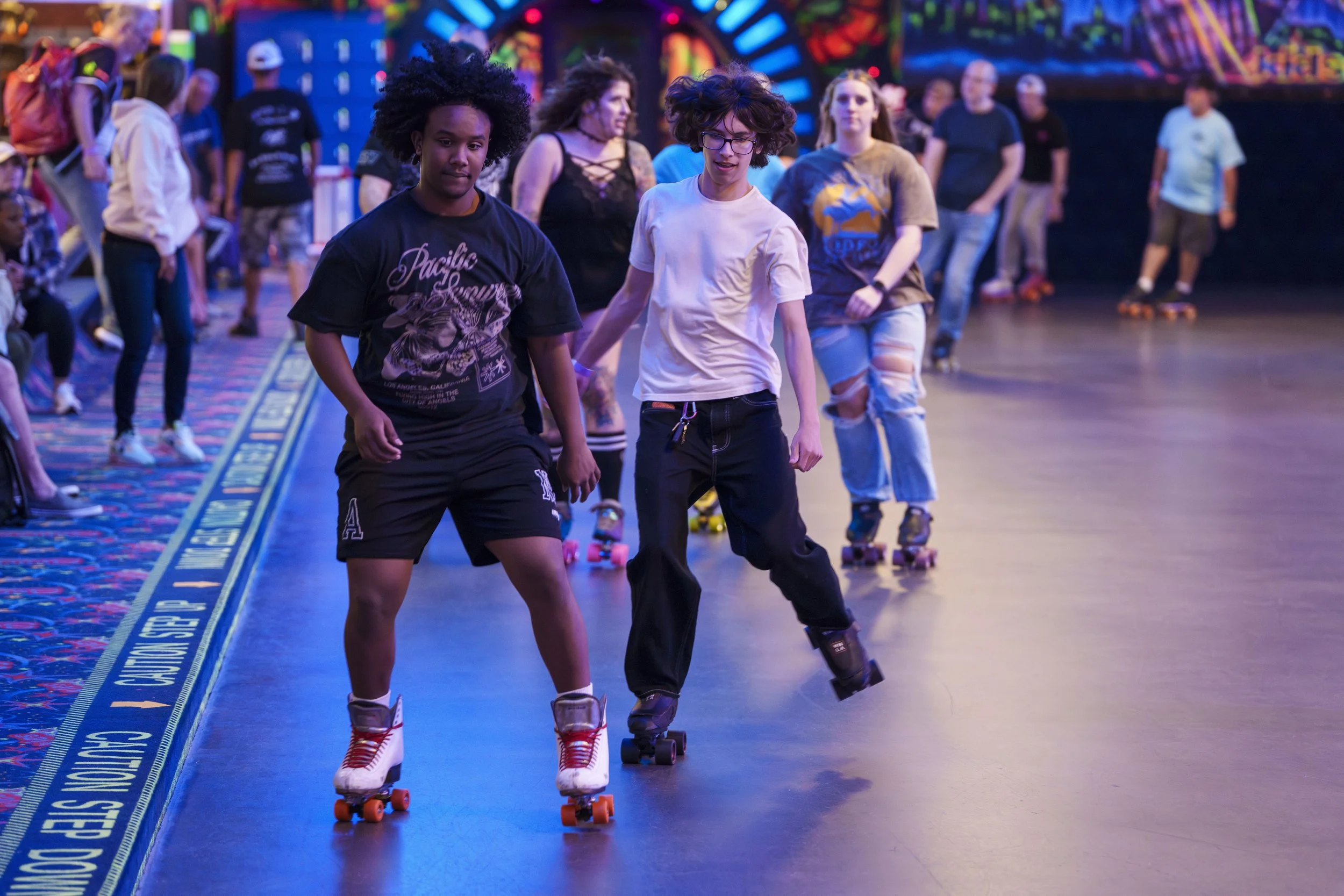 People roller skating at an indoor skating rink with colorful lights and decorations.