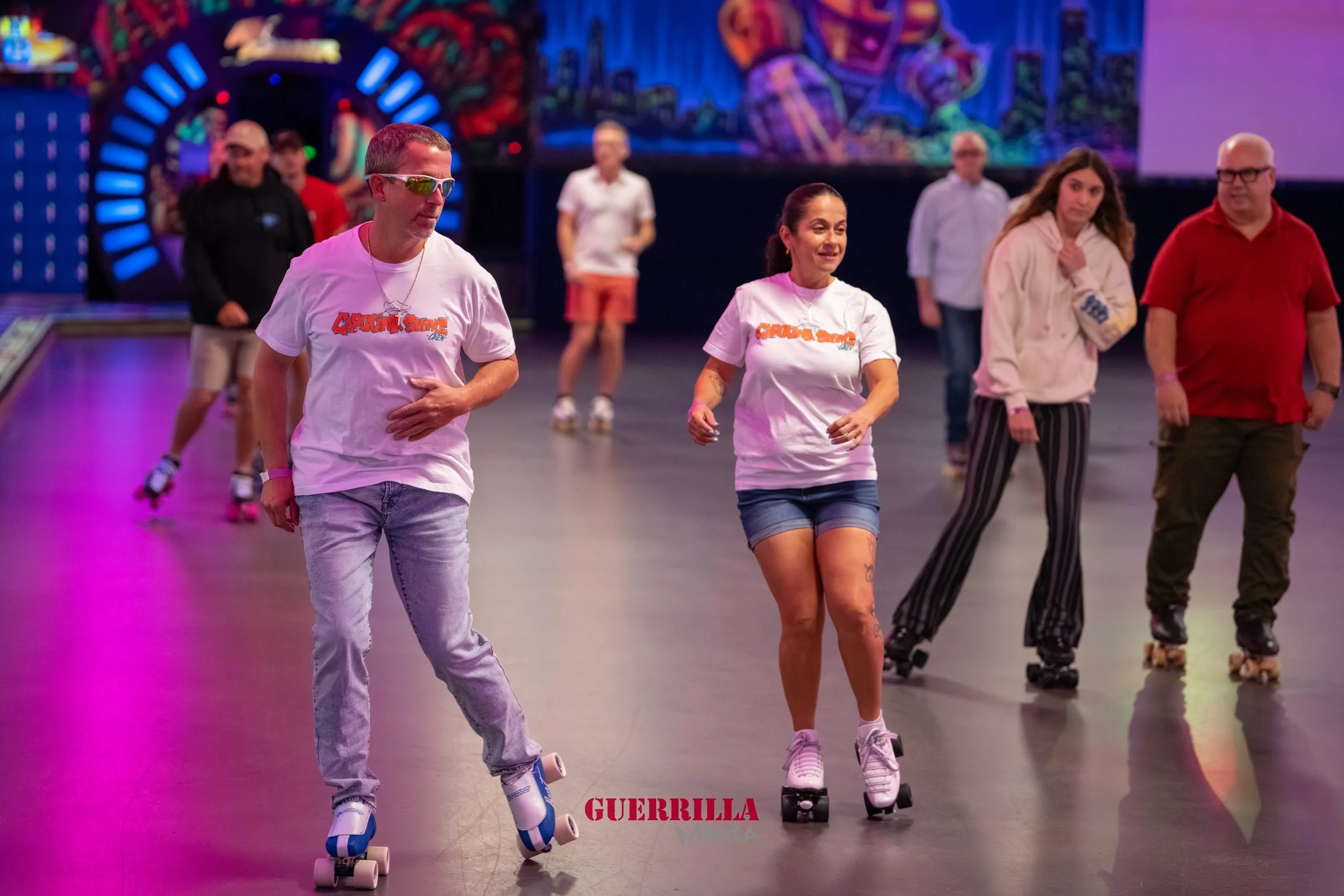 People roller skating in an indoor roller rink with colorful graffiti-style artwork on the walls.