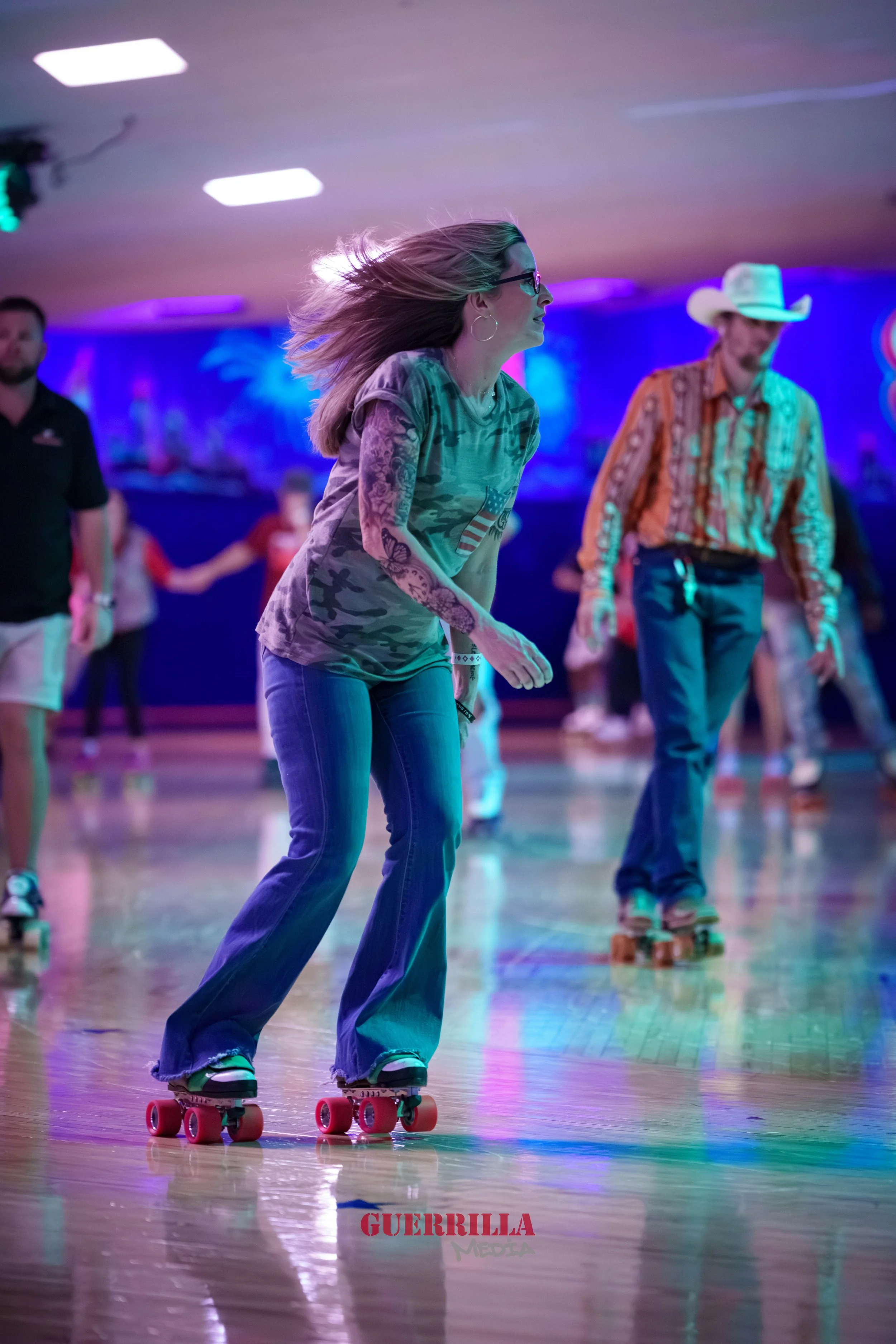 A woman roller skating in a roller rink with others in the background, colorful lighting, and a wooden floor.