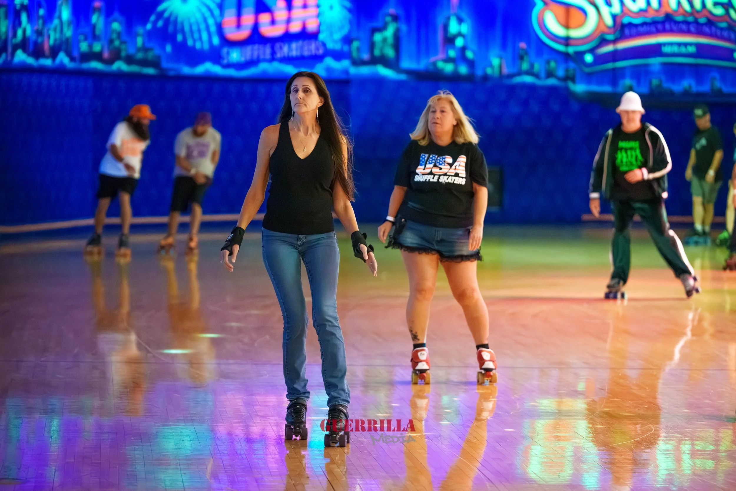 People roller skating indoors with colorful neon lights and signs in the background.