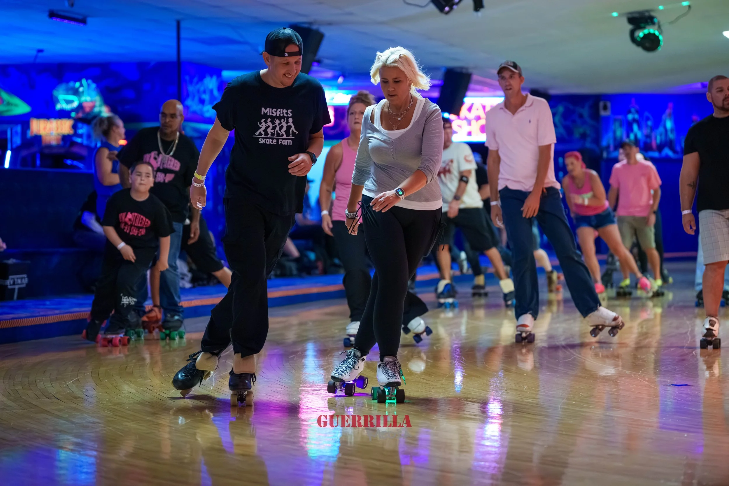 People roller skating in an indoor roller rink with colorful lights and neon signs.