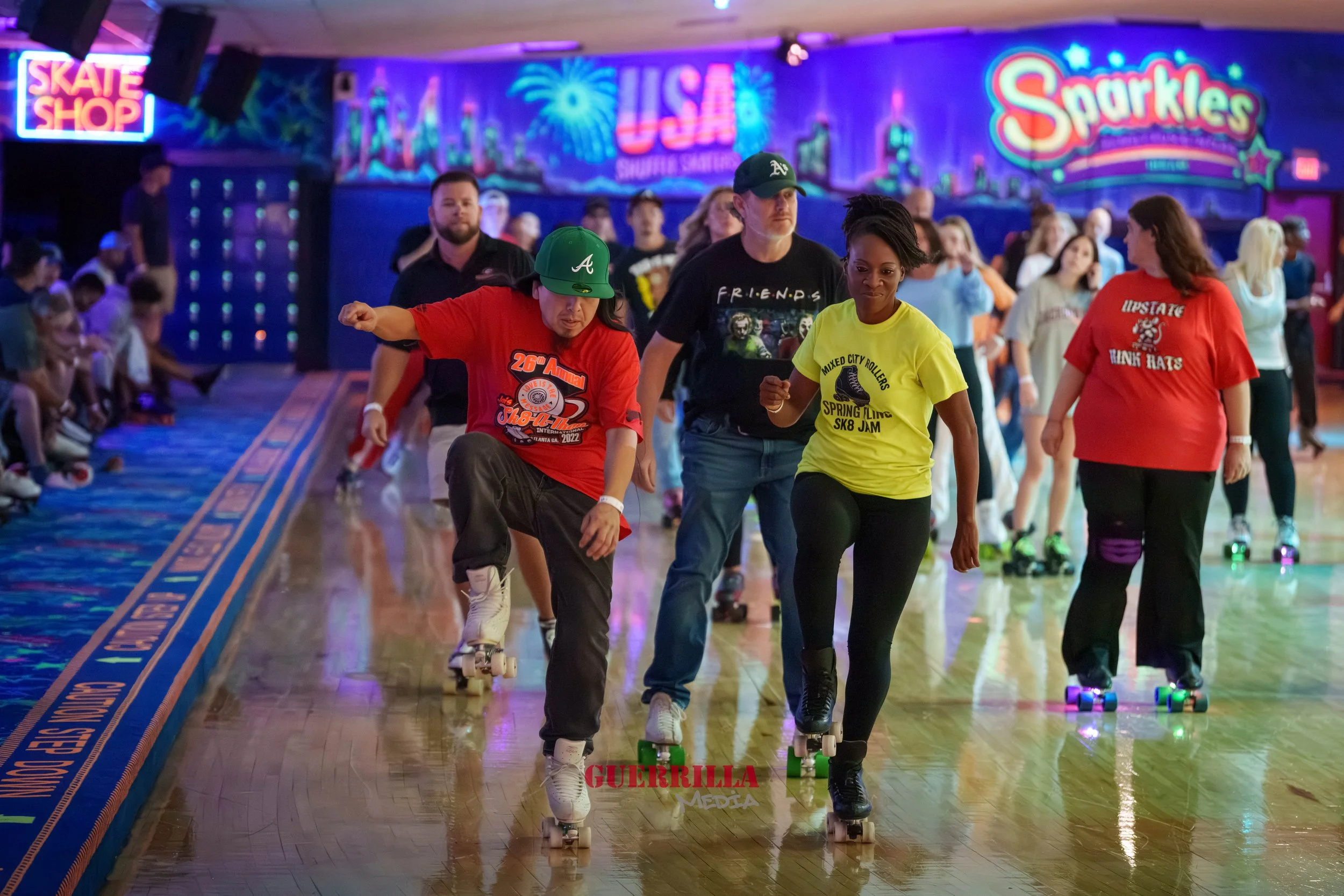 People roller skating indoors at a roller rink with colorful neon signs and a vibrant cityscape mural in the background.