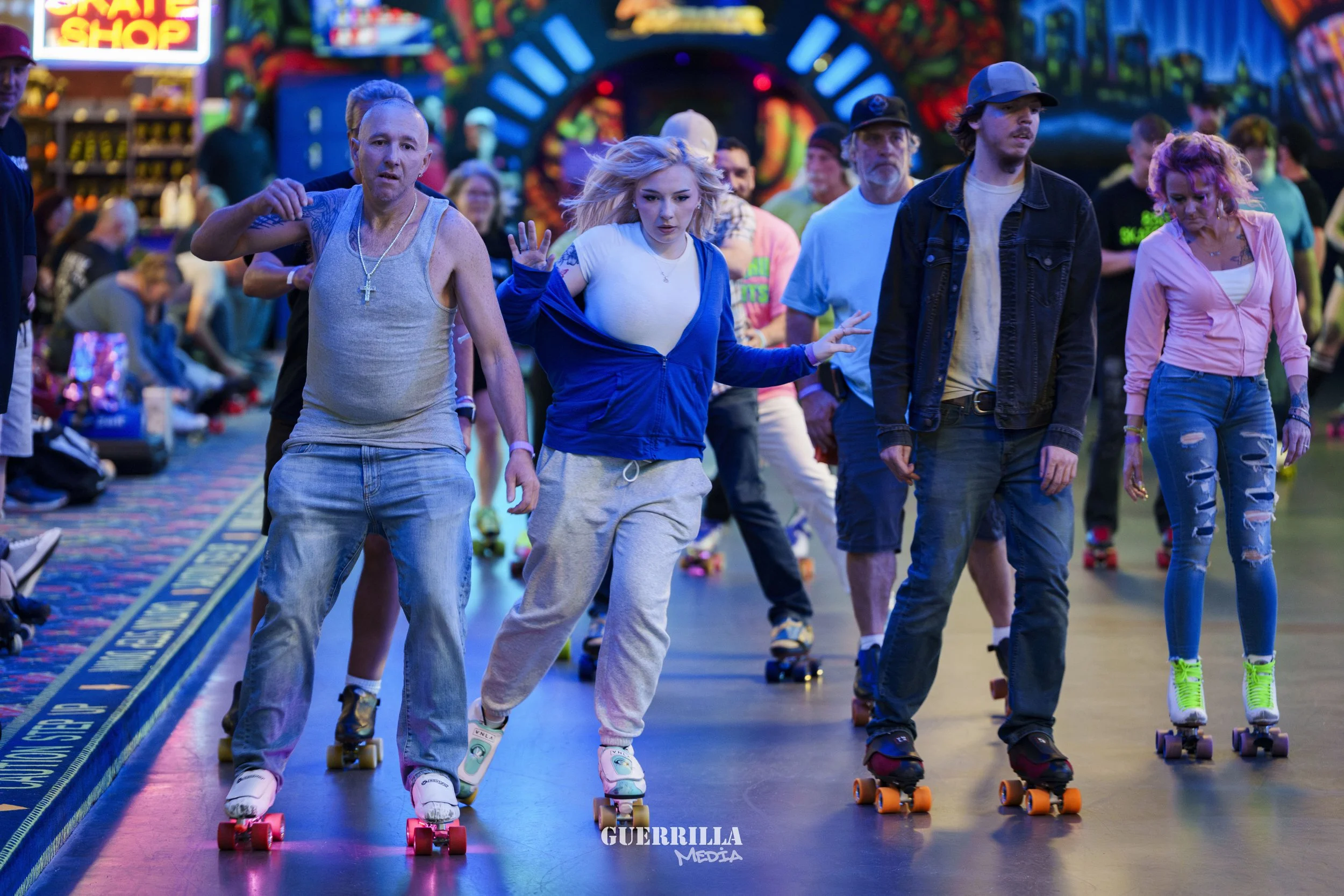 People roller skating at an indoor roller skating rink with colorful neon lights and arcade games in the background.