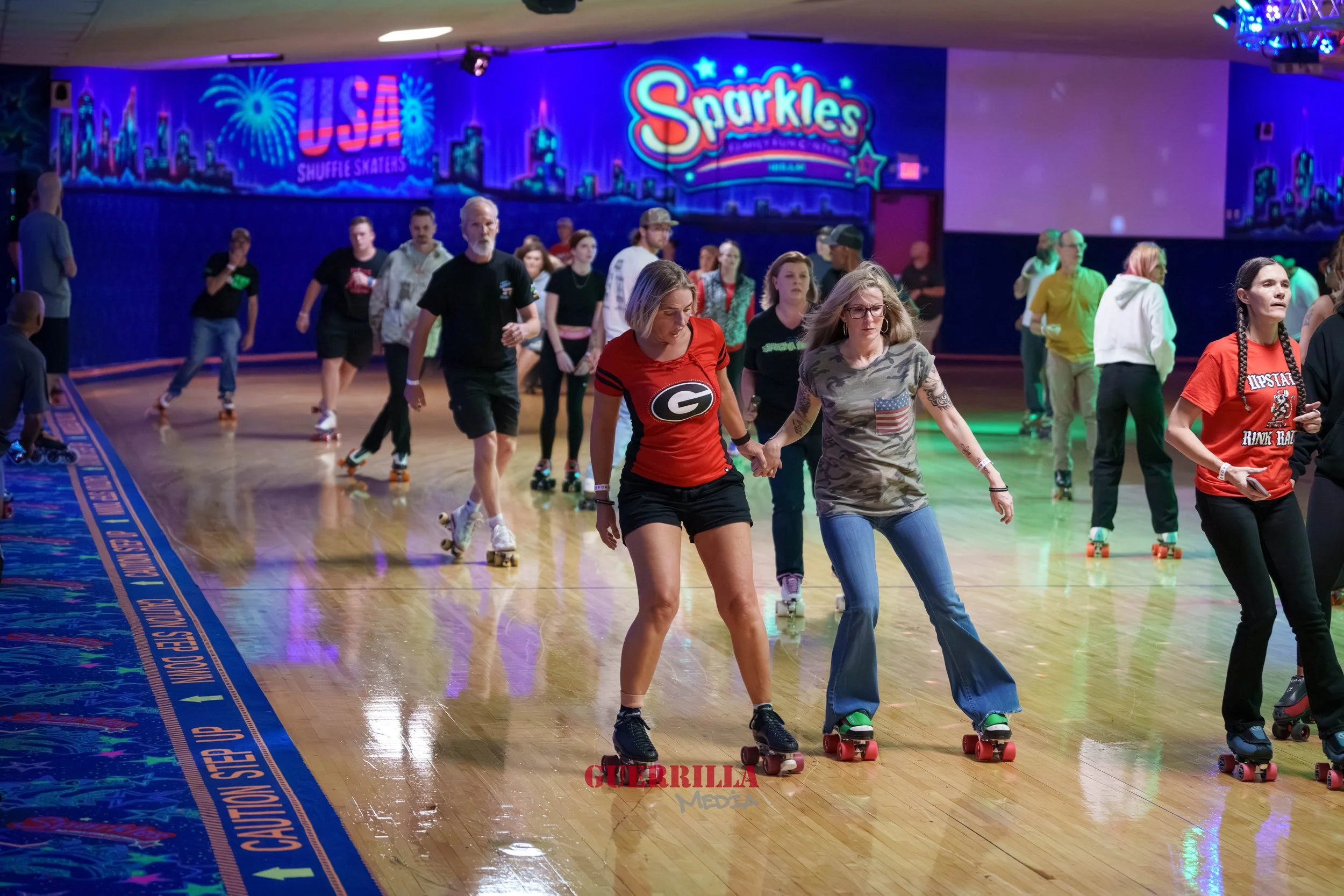People roller skating at an indoor skating rink with colorful lights and neon signs, including 'Sparkles' and 'USA Shuffle Skaters'.