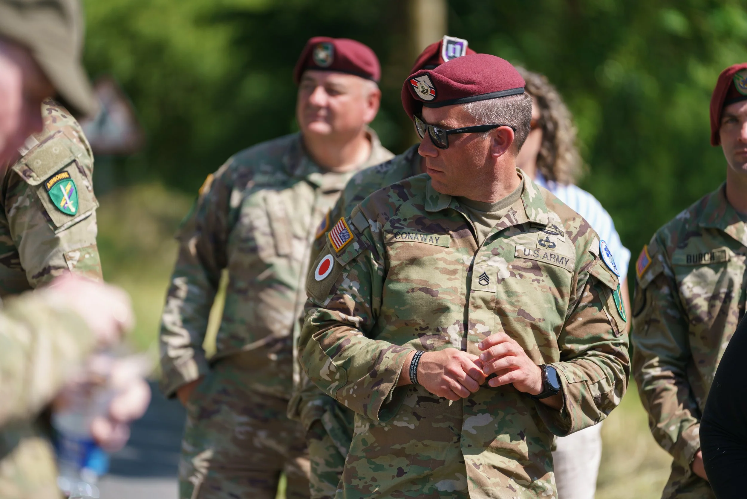 Military personnel in camouflage uniforms and maroon berets standing outdoors during a gathering or briefing.