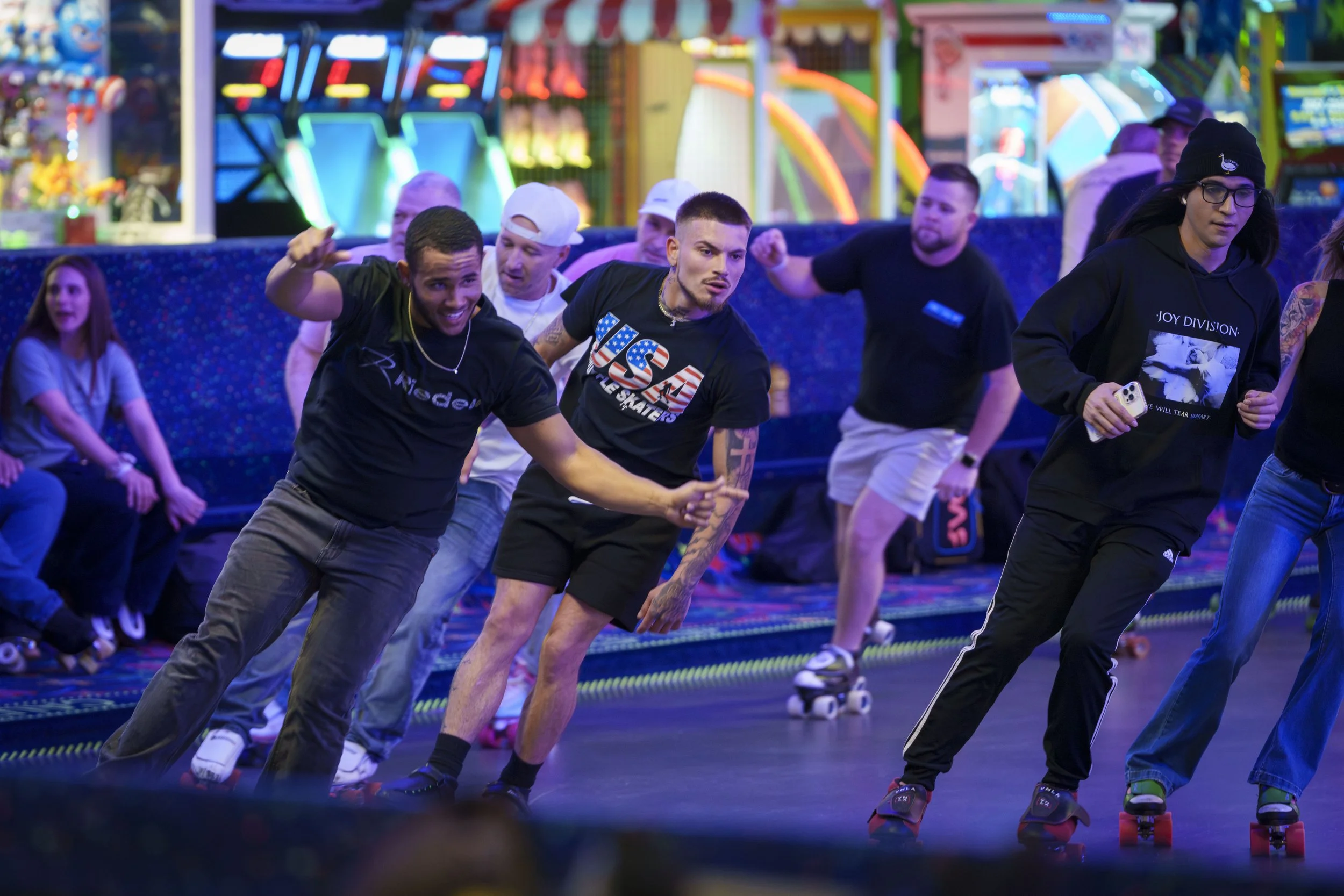 People roller skating at an arcade with bright colorful lights in the background.