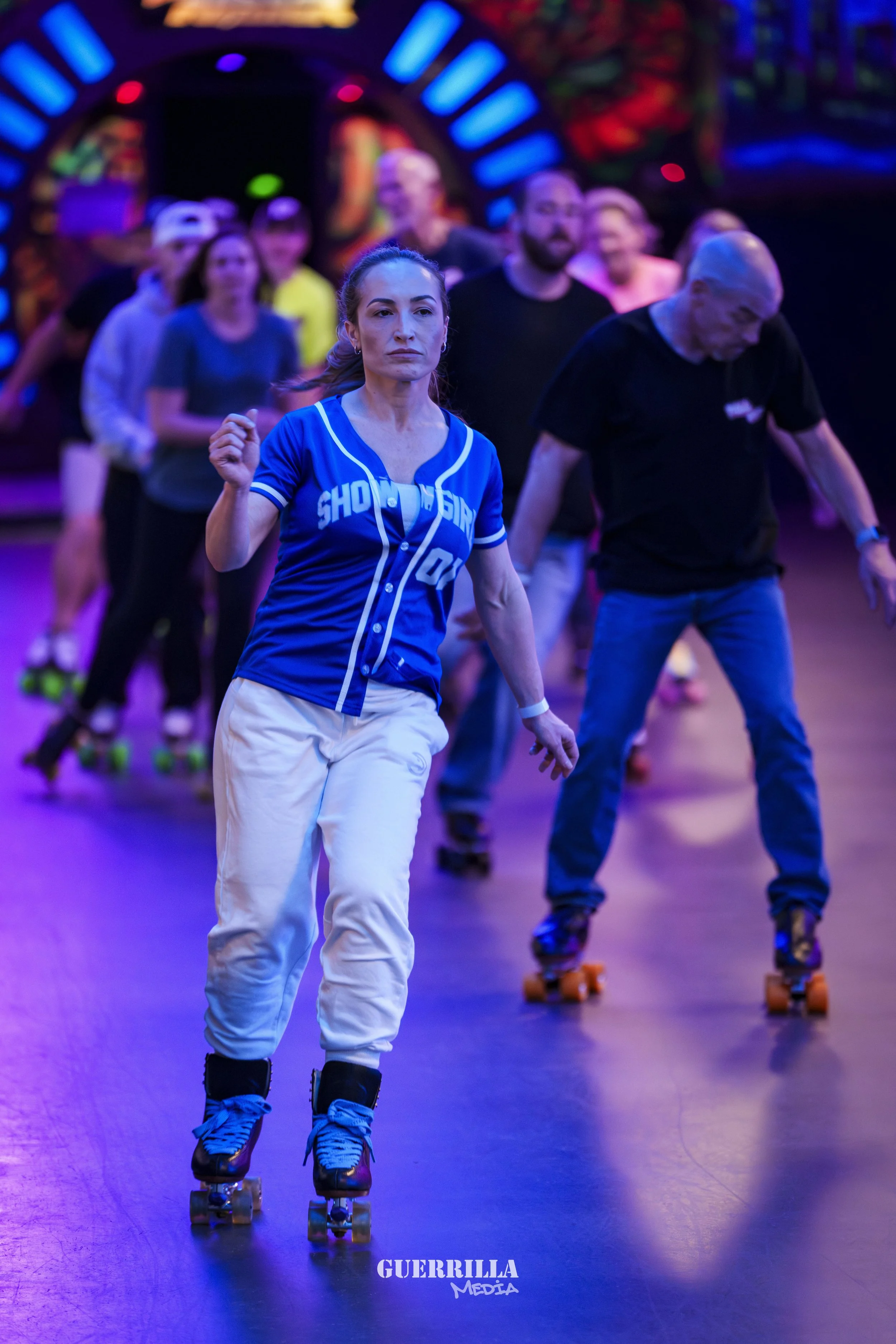 Women roller skating in a party or dance setting with colorful neon lights, some wearing sports jerseys and casual clothes.