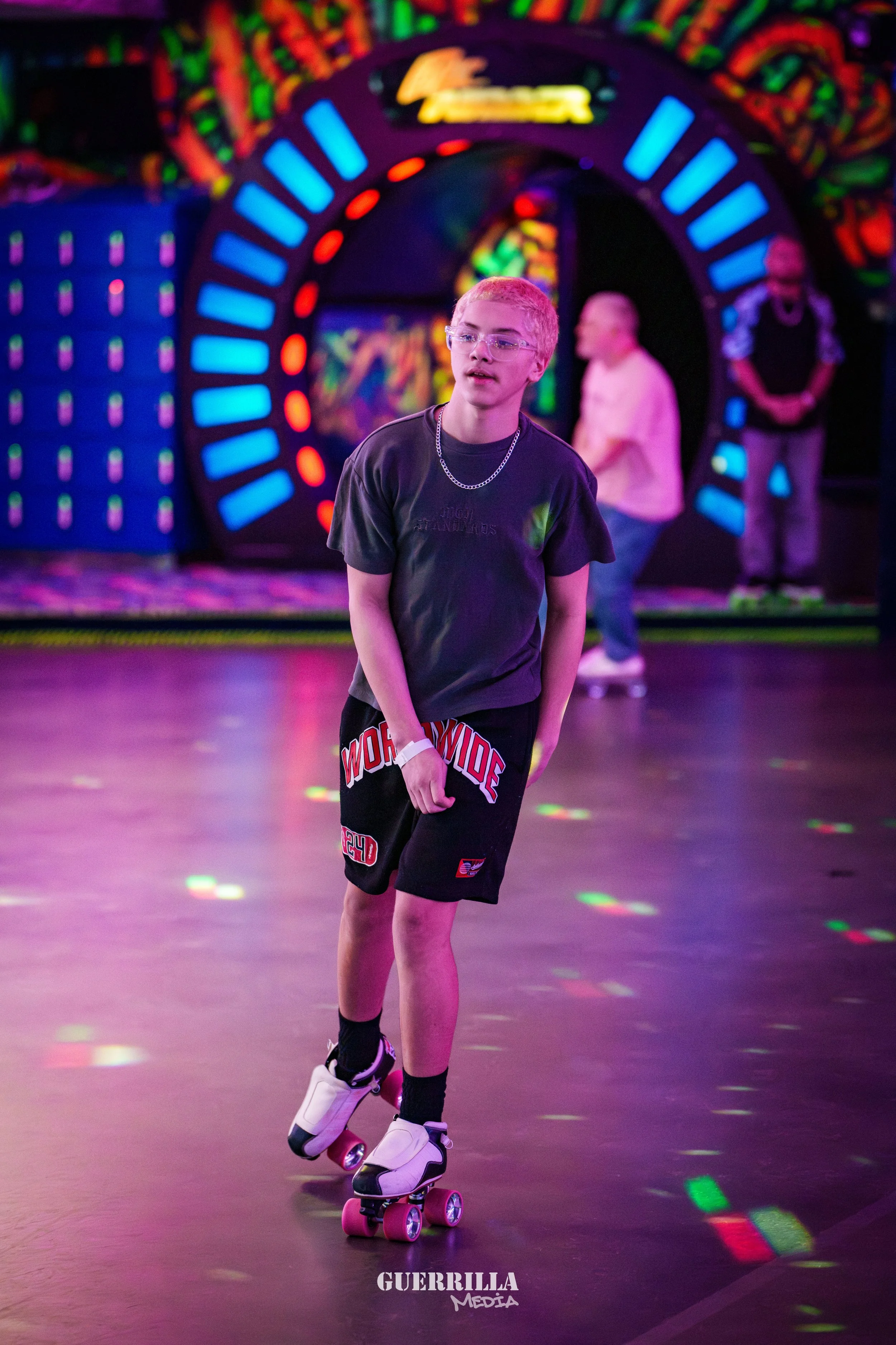 A boy roller skating at an indoor roller rink with colorful neon lights and artwork in the background.