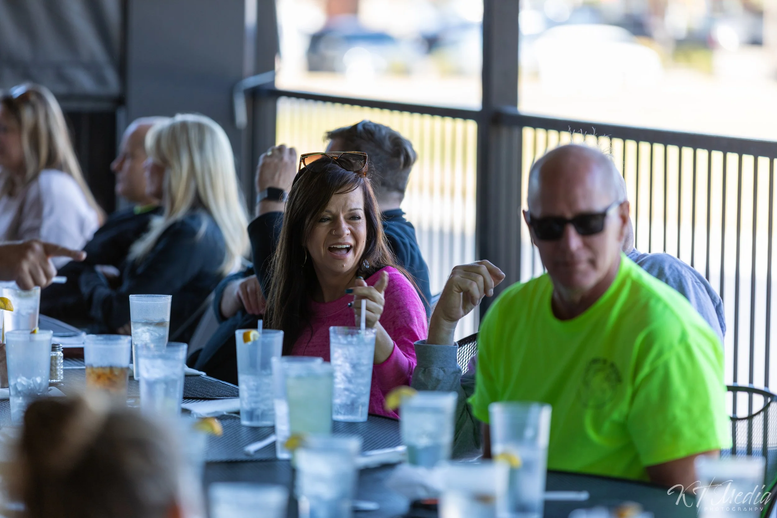 People sitting at a restaurant table outside, drinking water, and chatting.