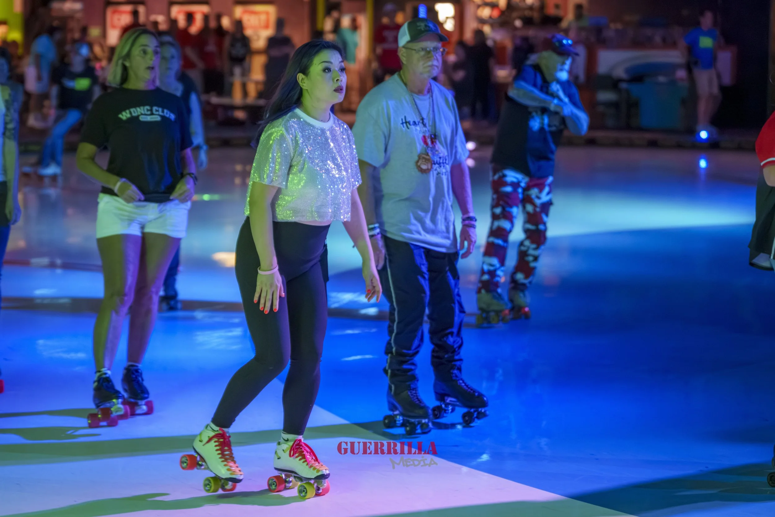 People roller skating in a dimly lit indoor skating rink with colorful lights.
