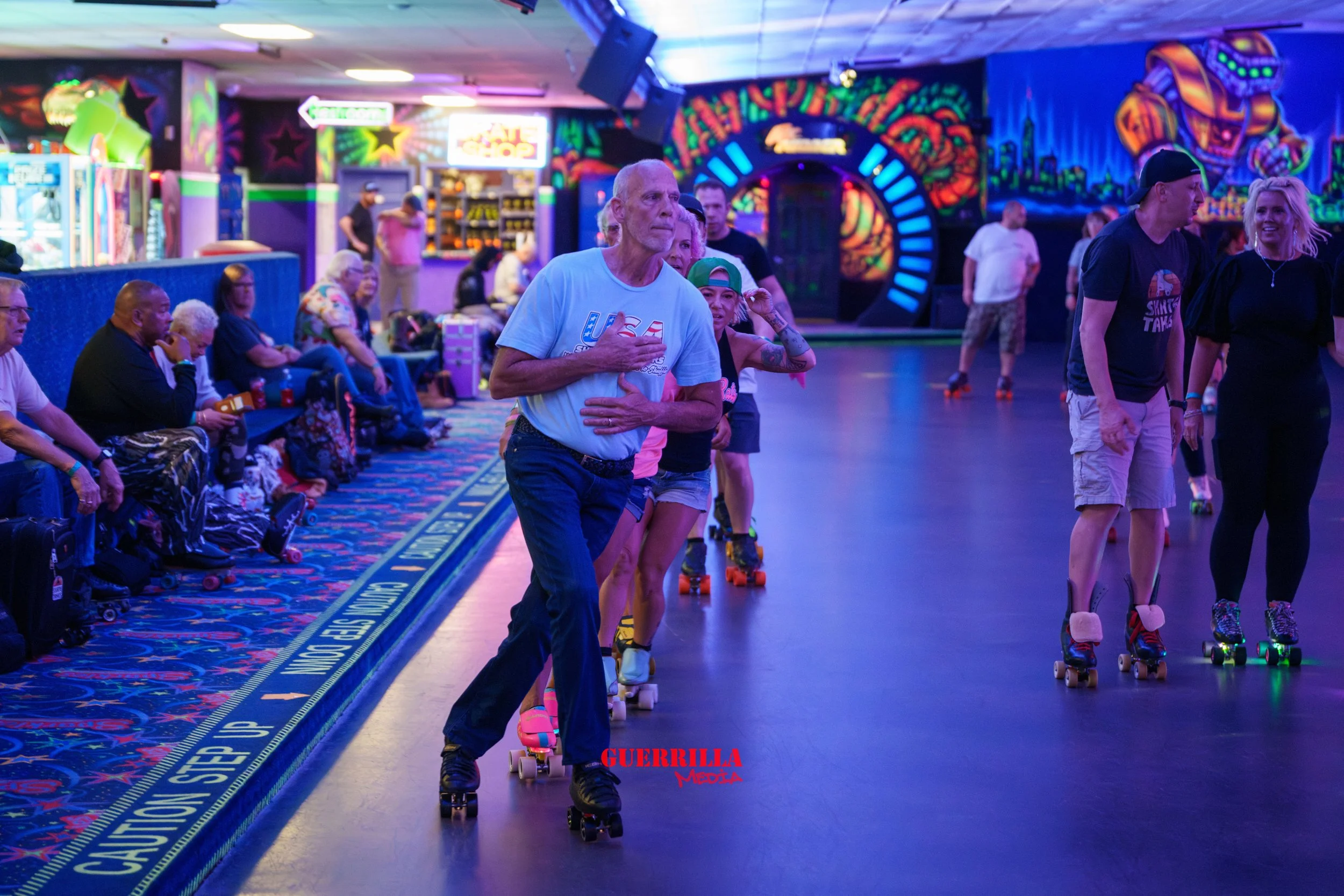 People roller skating inside an arcade with colorful neon lights and graffiti-style artwork on the walls