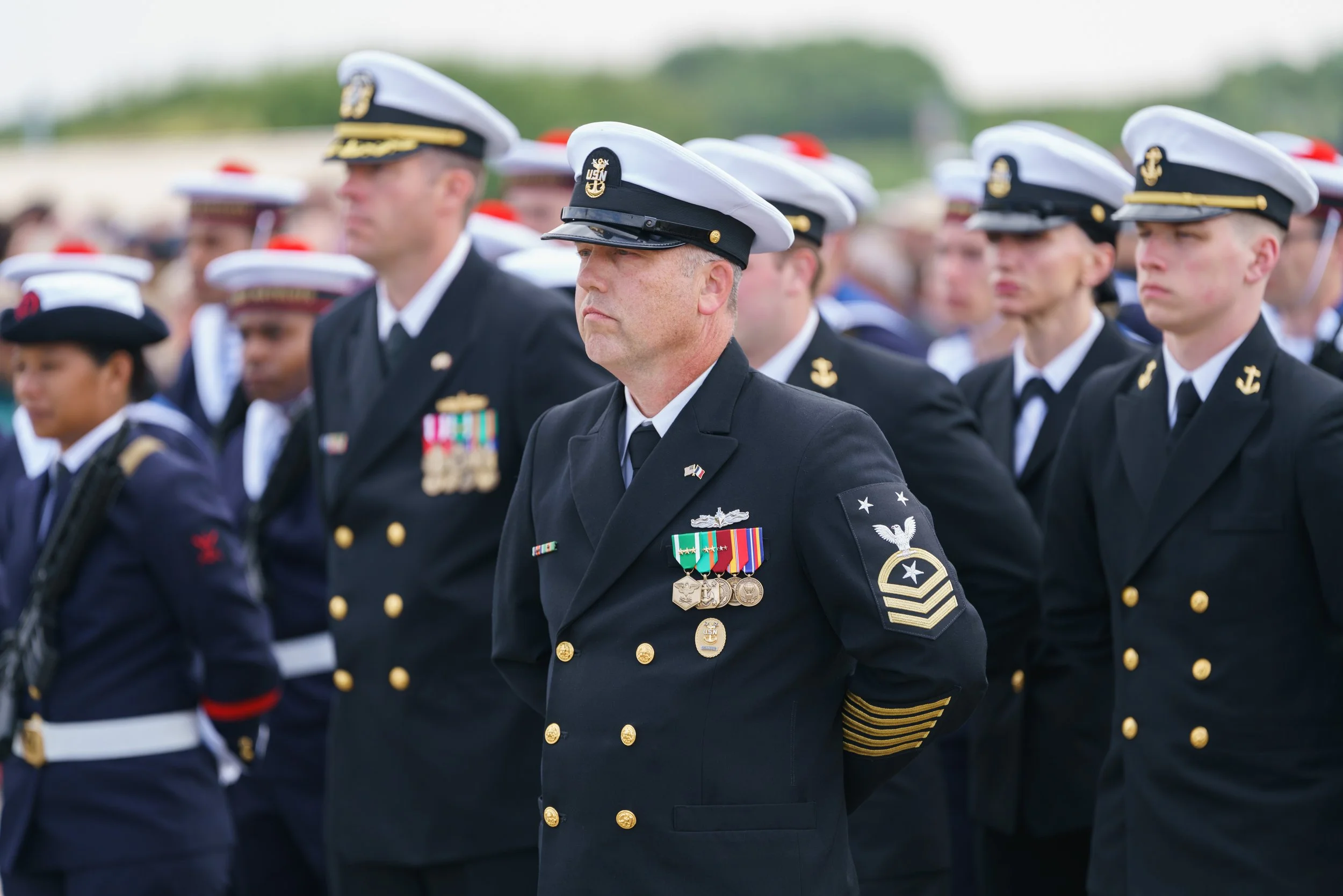 U.S. Navy personnel in uniform standing at attention during a ceremony or memorial event.