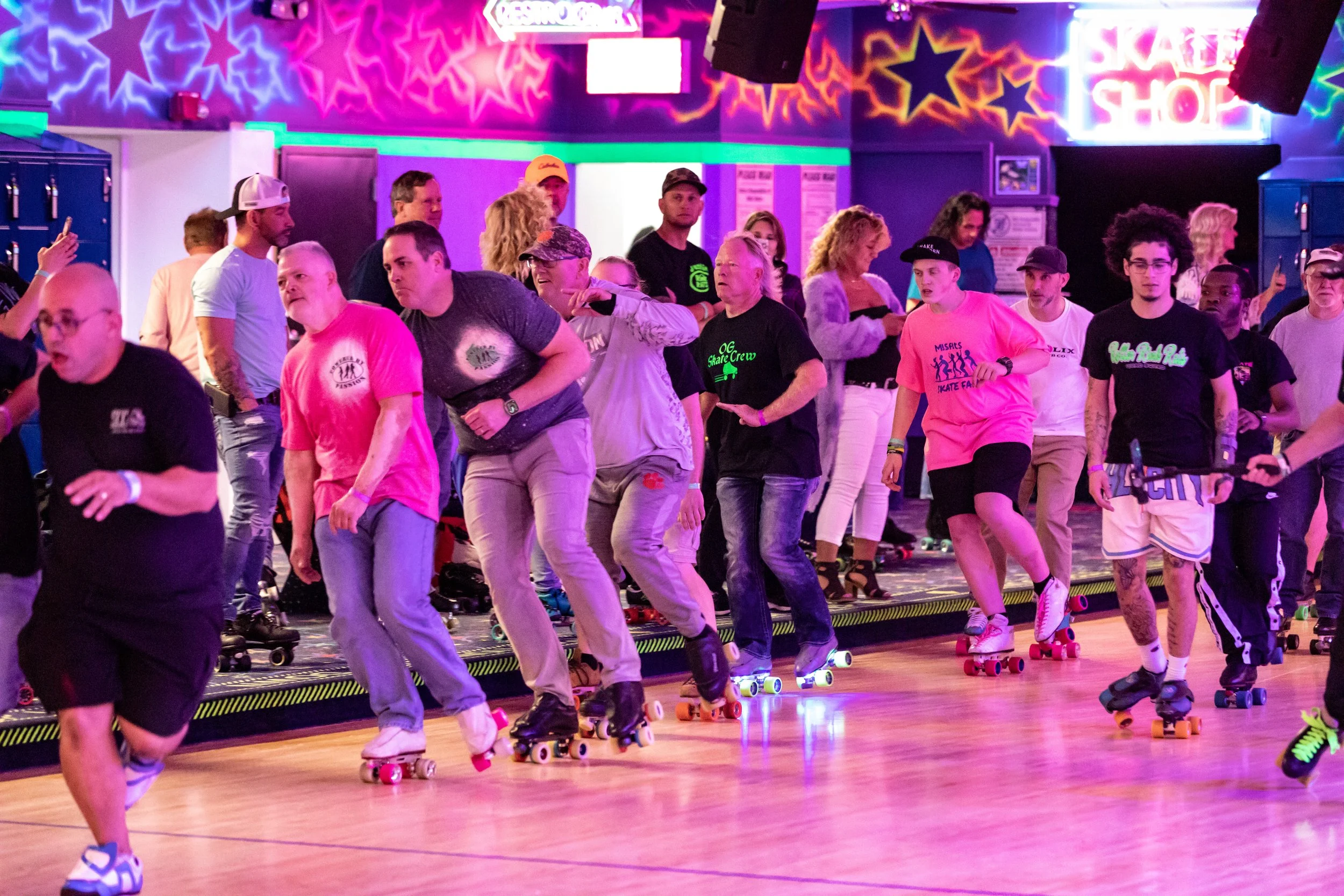 People roller skating at an indoor skating rink with colorful star and neon lights on the walls.