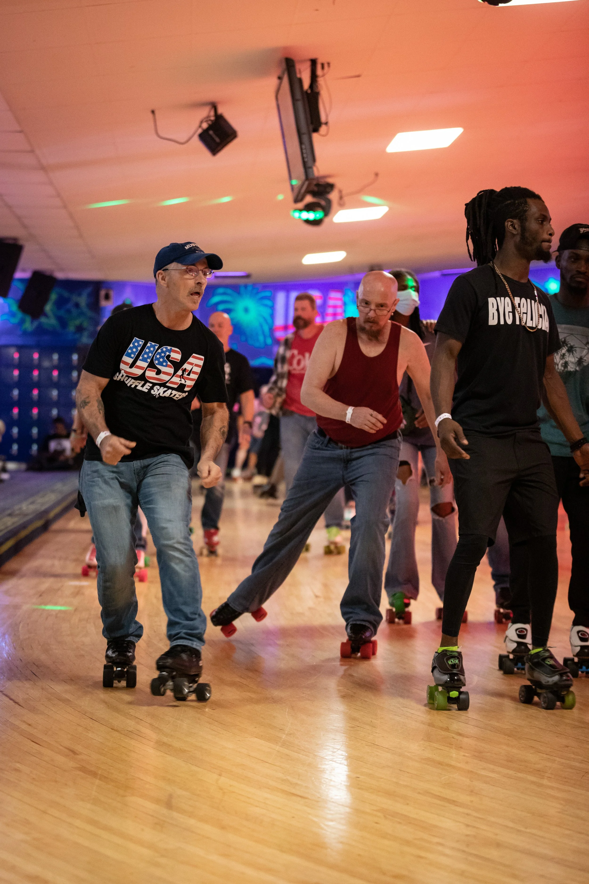 People roller skating in indoor roller rink with colorful lighting and wall decorations.