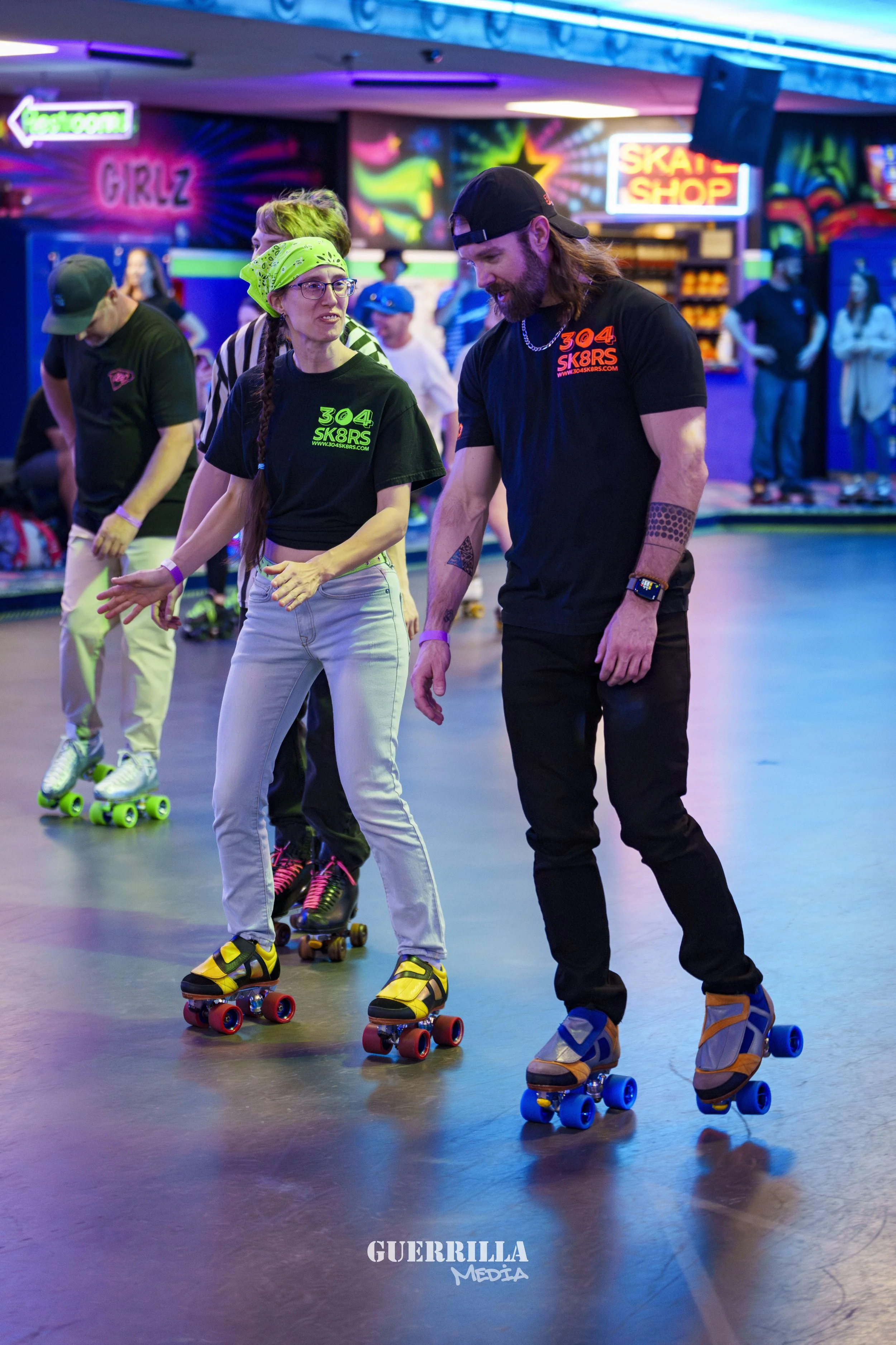 People roller skating inside an entertainment venue with colorful neon lights and signs that say "Girlz" and "Skate Shop."