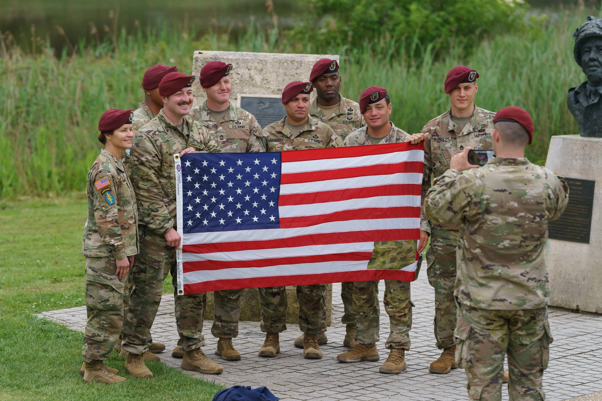 Military personnel in uniform holding an American flag during a commemorative event.
