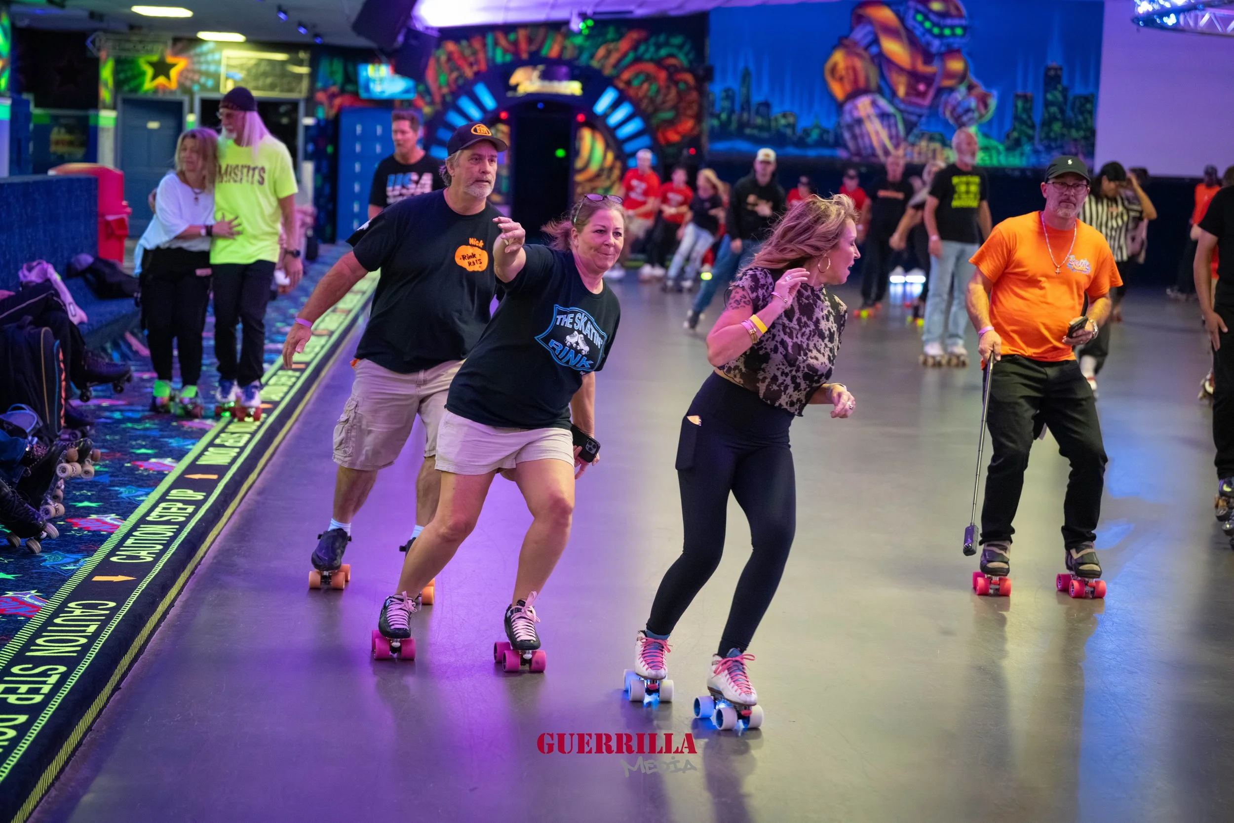 People roller skating inside an arcade or roller rink with colorful graffiti and neon lights in the background, some of them appear to be having fun and enjoying the activity.