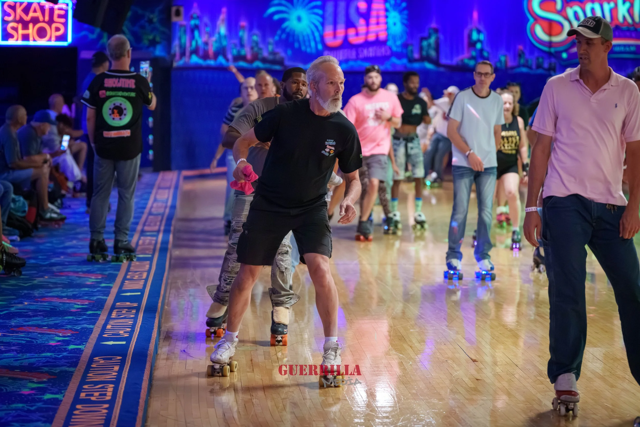 People roller skating inside an indoor roller rink with colorful neon lights and decorations, including a neon sign for a skate shop and a vibrant cityscape mural in the background.