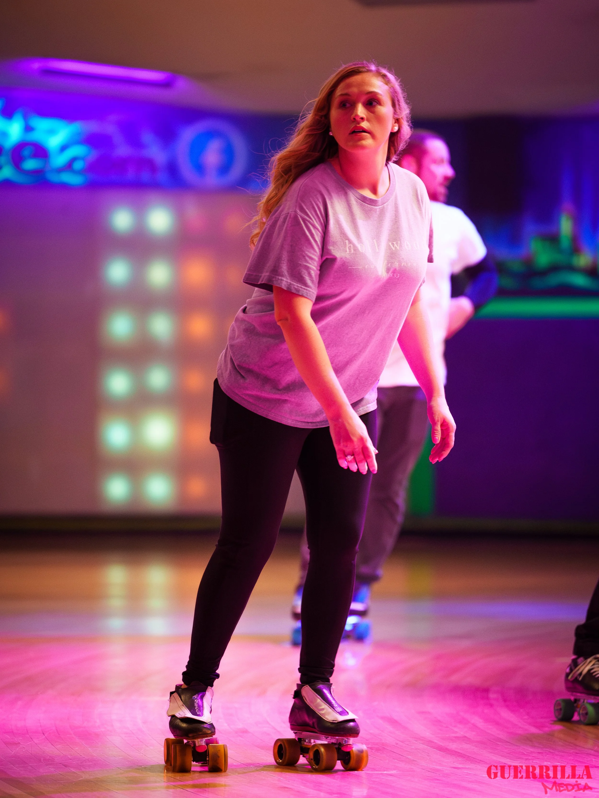 A young woman roller skating indoors with neon lighting in the background.