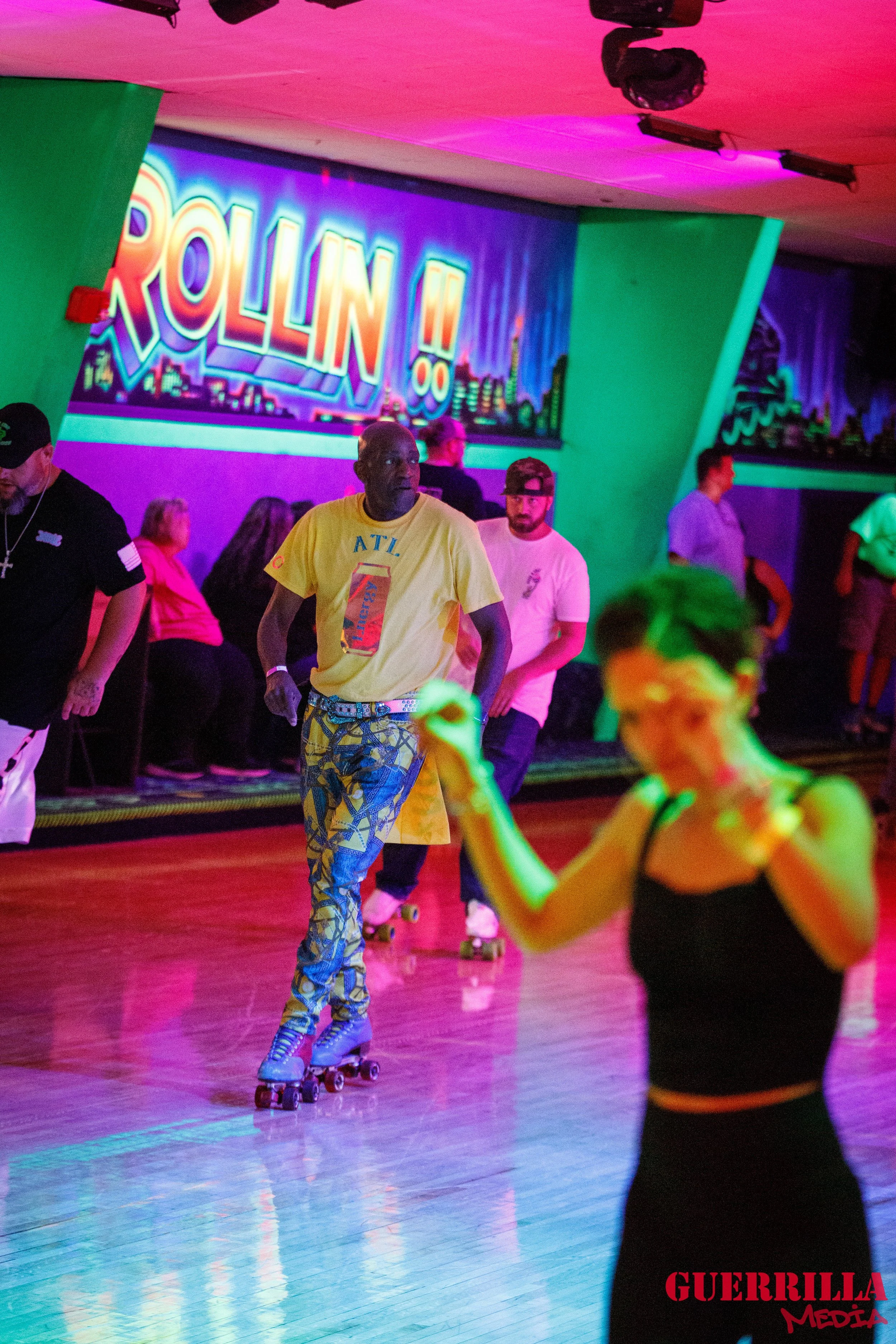 People roller skating in a colorful, neon-lit roller rink with a large 'ROLLIN' sign in the background.
