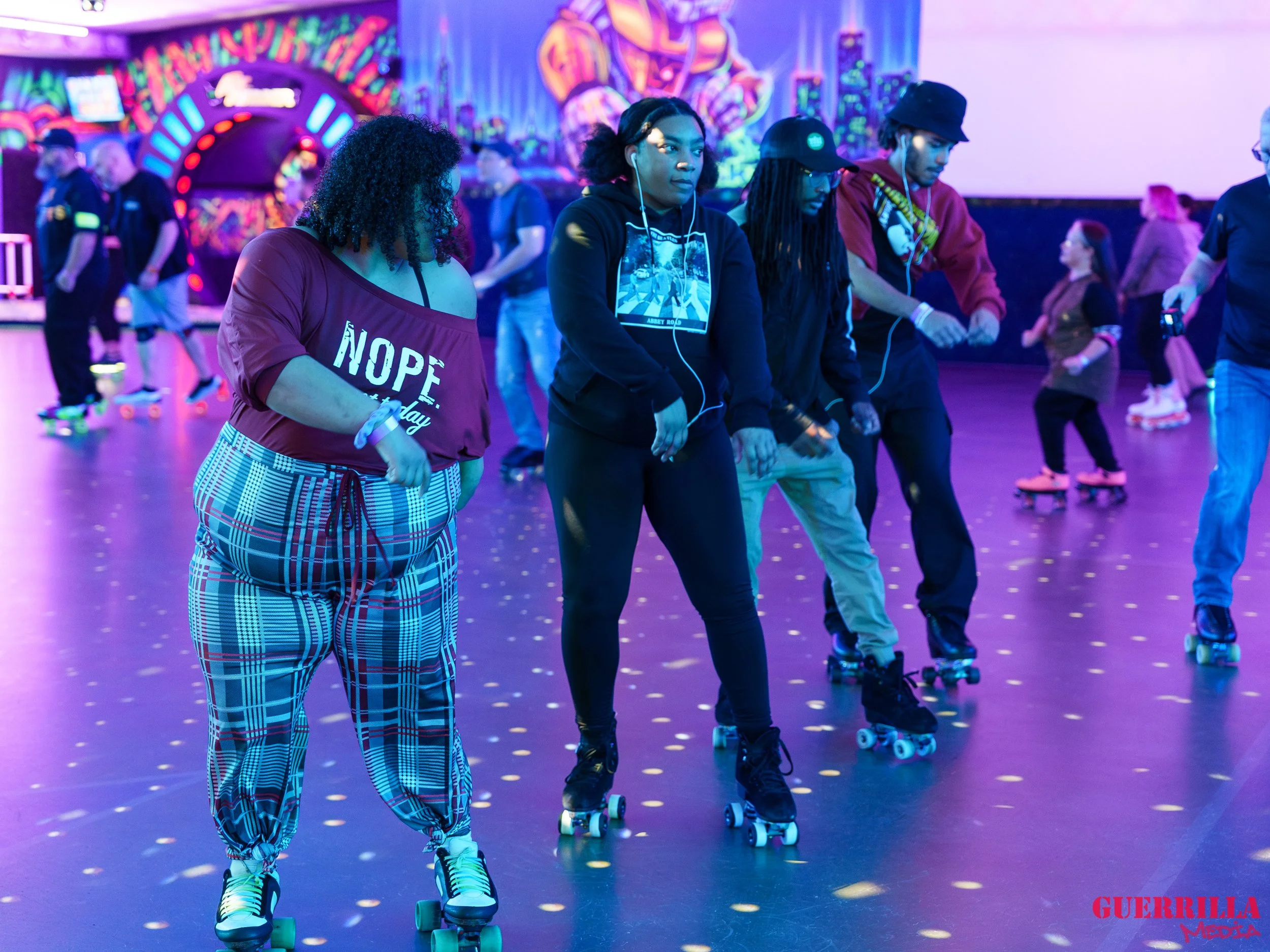 People roller skating under colorful neon lights, with graffiti-style art on the walls in the background.
