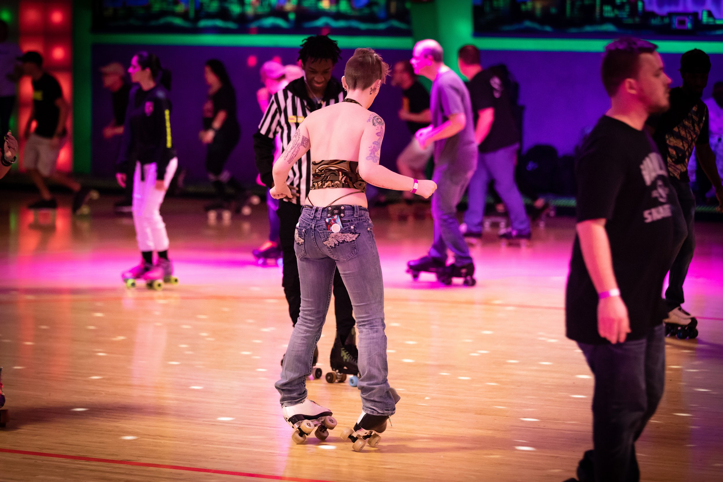 People roller skating at an indoor roller rink with colorful neon lighting.