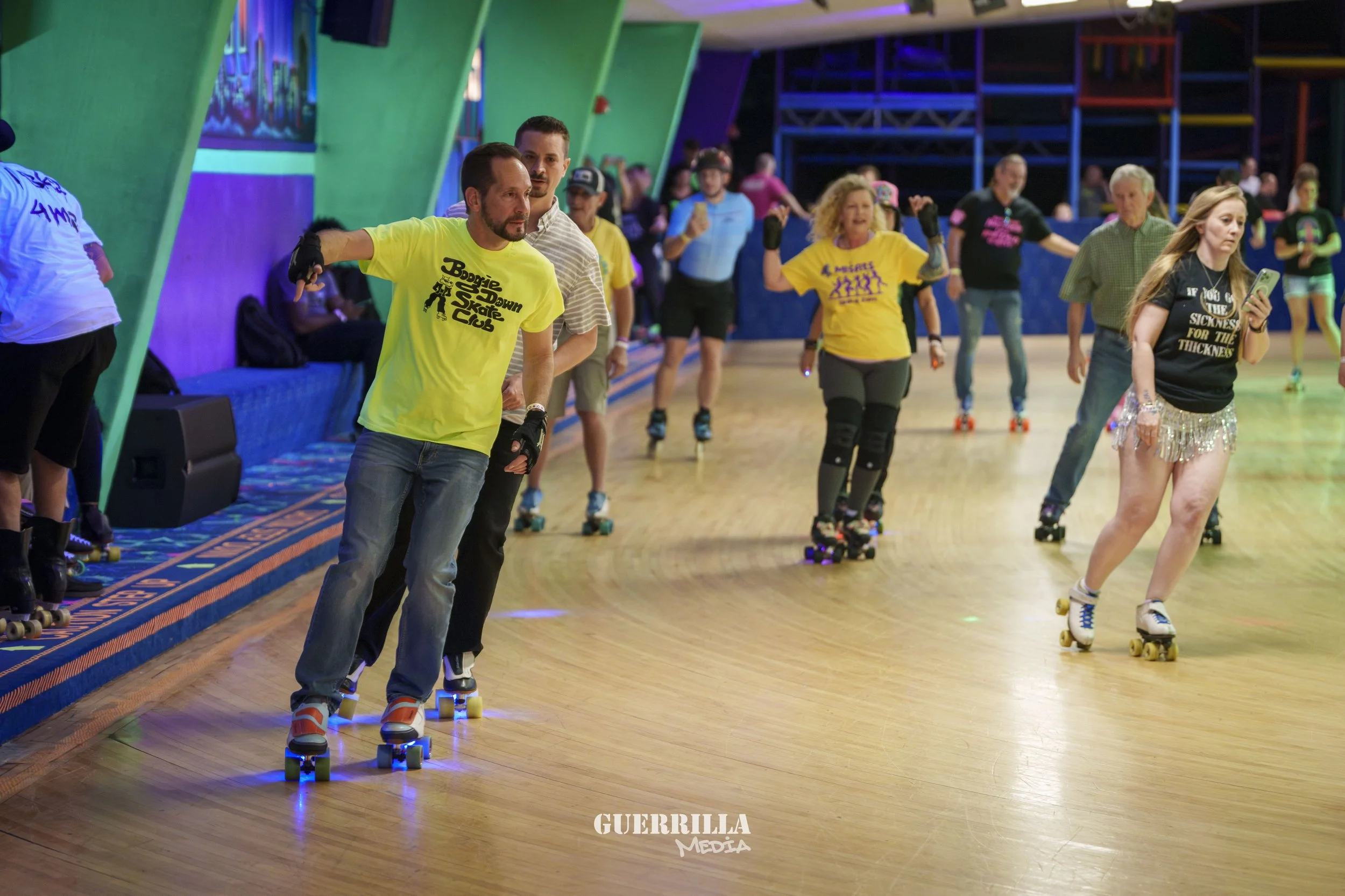 People roller skating at an indoor rink with colorful lights and wooden floors