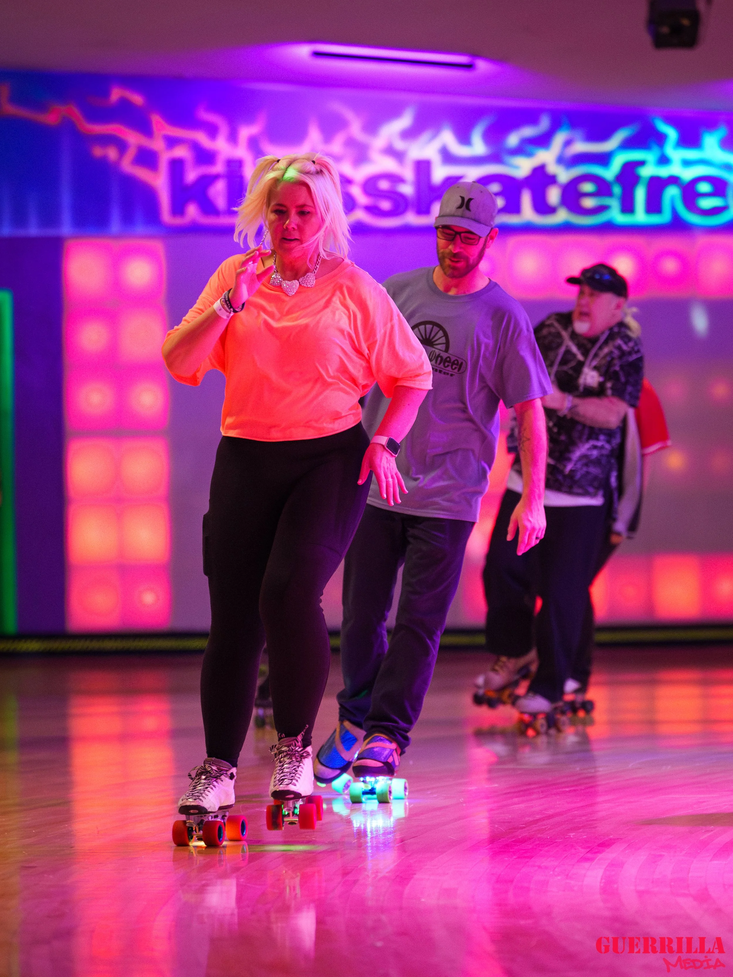 People roller skating in a neon-lit roller rink.