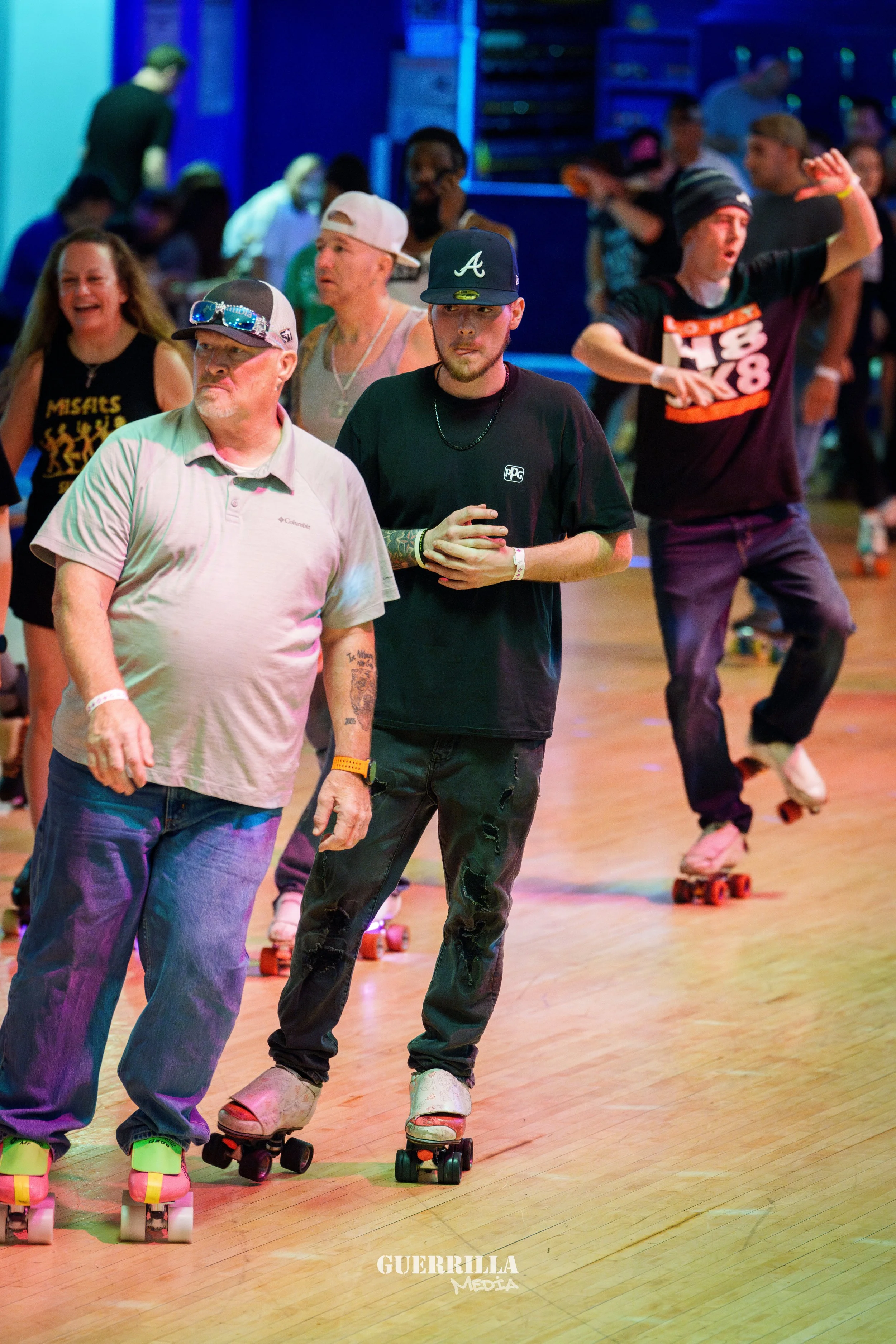 People roller skating indoors at a lively event with colorful lighting and spectators in the background.