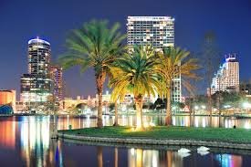 Night view of the Tampa skyline with illuminated buildings and palm trees reflecting off the waterfront.