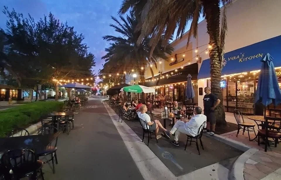 People enjoying outdoor dining under string lights on a lively evening in downtown Clearwater, Florida.
