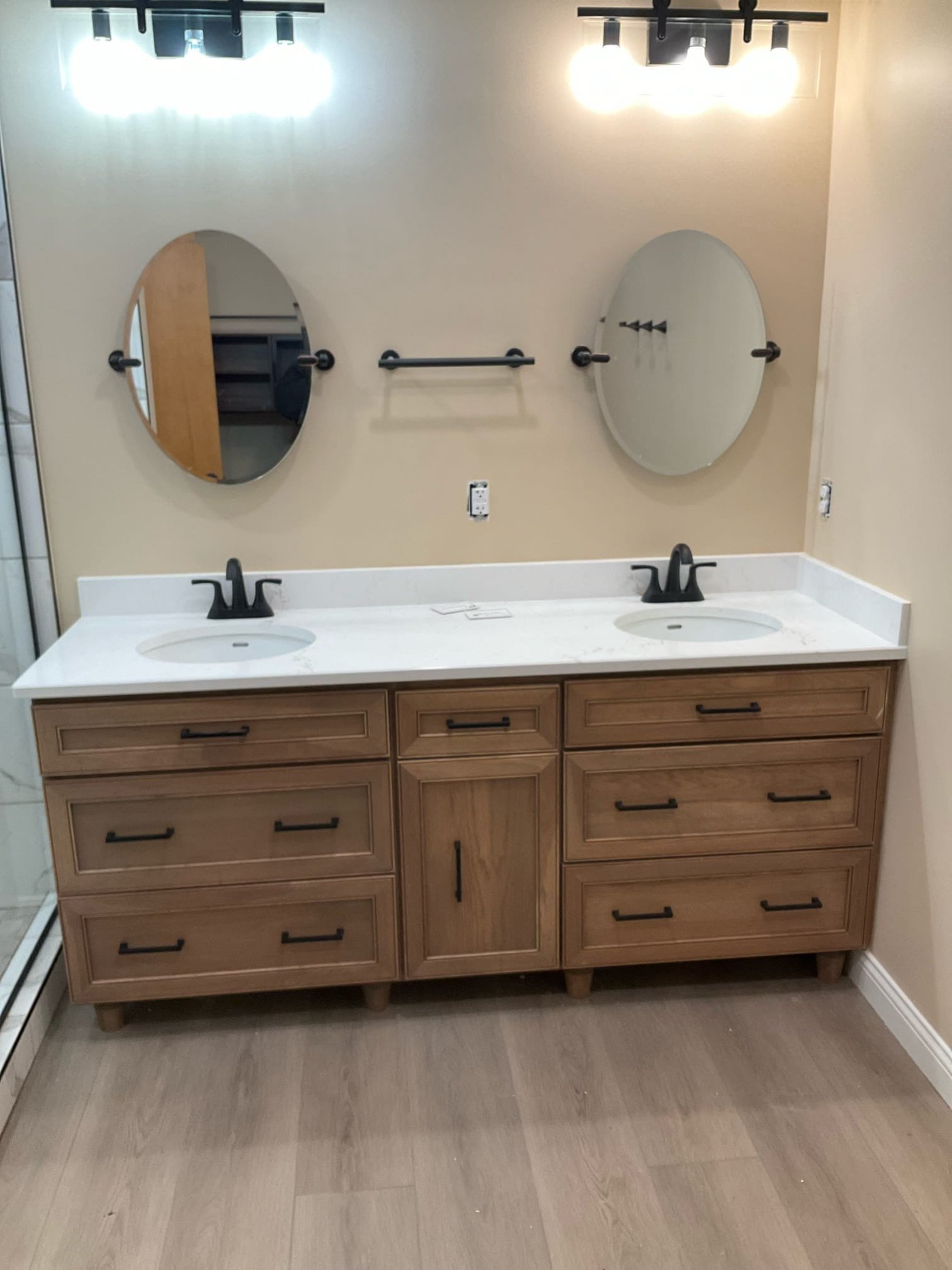 Modern double vanity installation with natural wood cabinetry, dual sinks, and matte black fixtures.