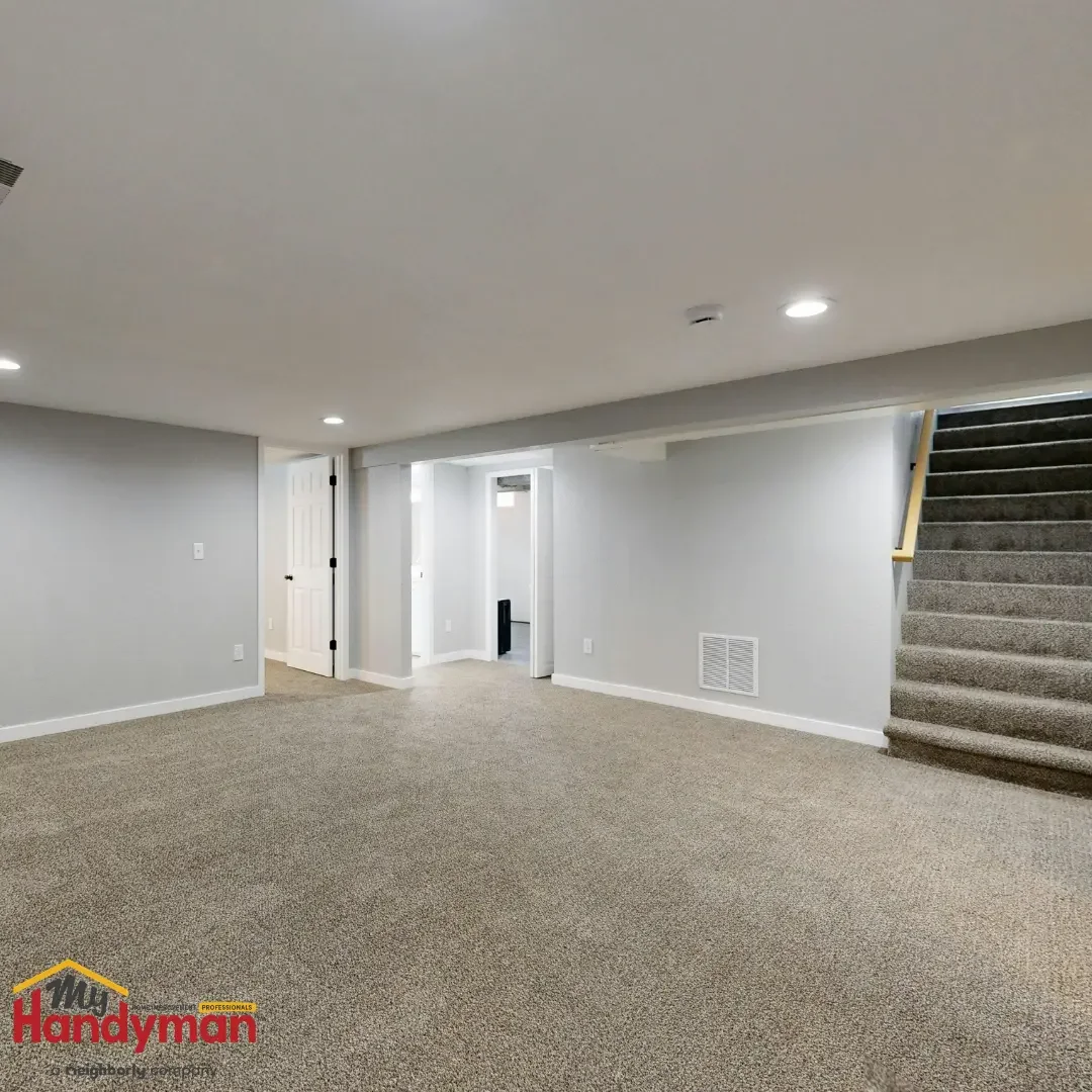 A finished but empty carpeted basement with recessed lighting and a staircase, a candidate space for custom built-ins, in a Saline, Michigan home.