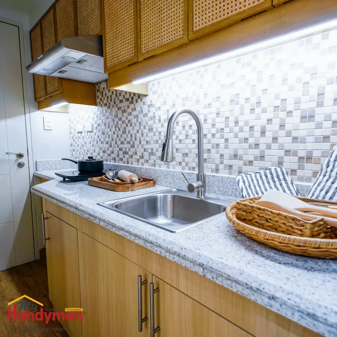 Stainless steel kitchen sink and pull-down faucet on a granite counter with a tile backsplash, served by a garbage disposal, in an Ann Arbor, Northern Michigan kitchen.