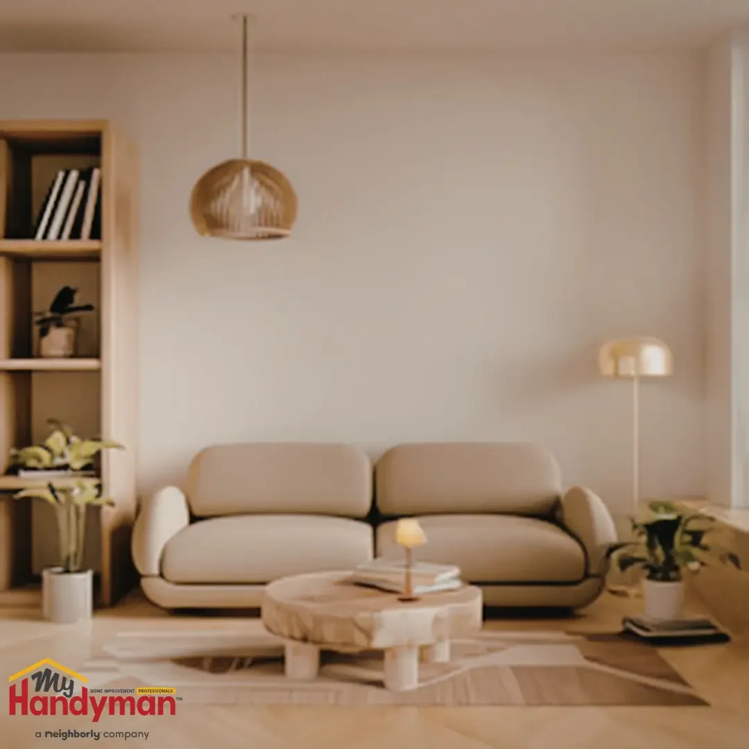 A minimalist living room with a large, cleanly painted neutral wall, a low sofa, a wood bookshelf, and a pendant light in a Saline, Michigan home.