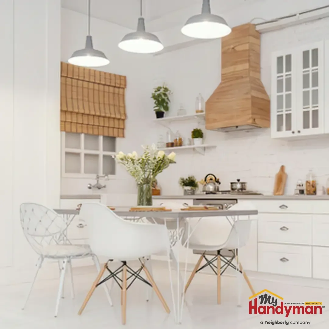 A bright white kitchen with a dining table, molded chairs, and pendant lights set up for summer entertaining in an Ann Arbor, Northern Michigan home.