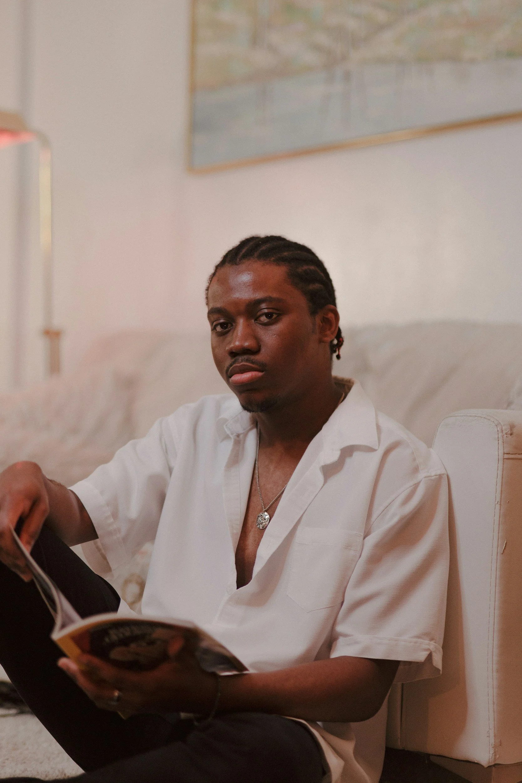 Adult man sitting on the floor in a calm living room holding a magazine, representing reflection emotional processing, and individual therapy.