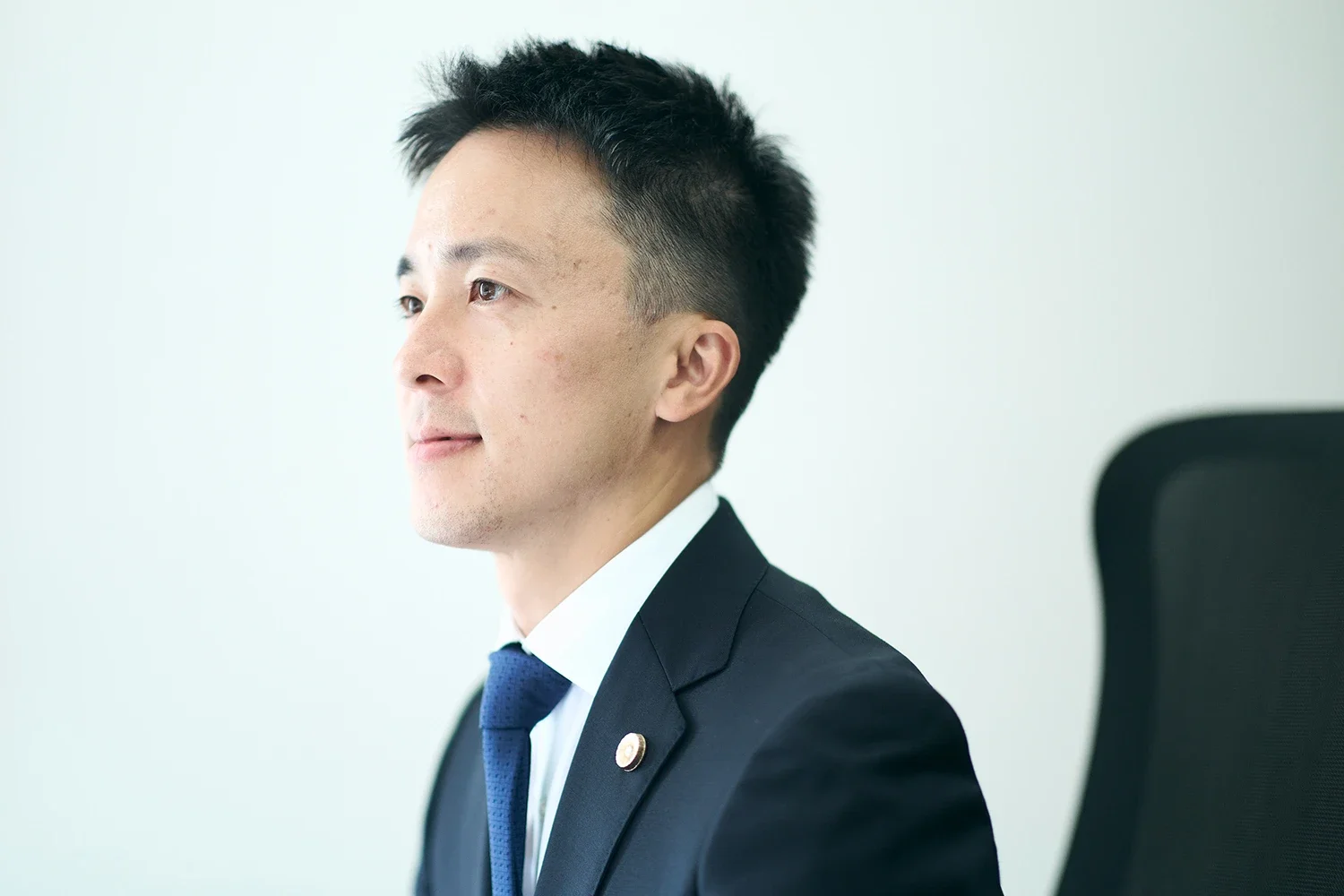 ジャケットを着た男性が横を向いて座っている