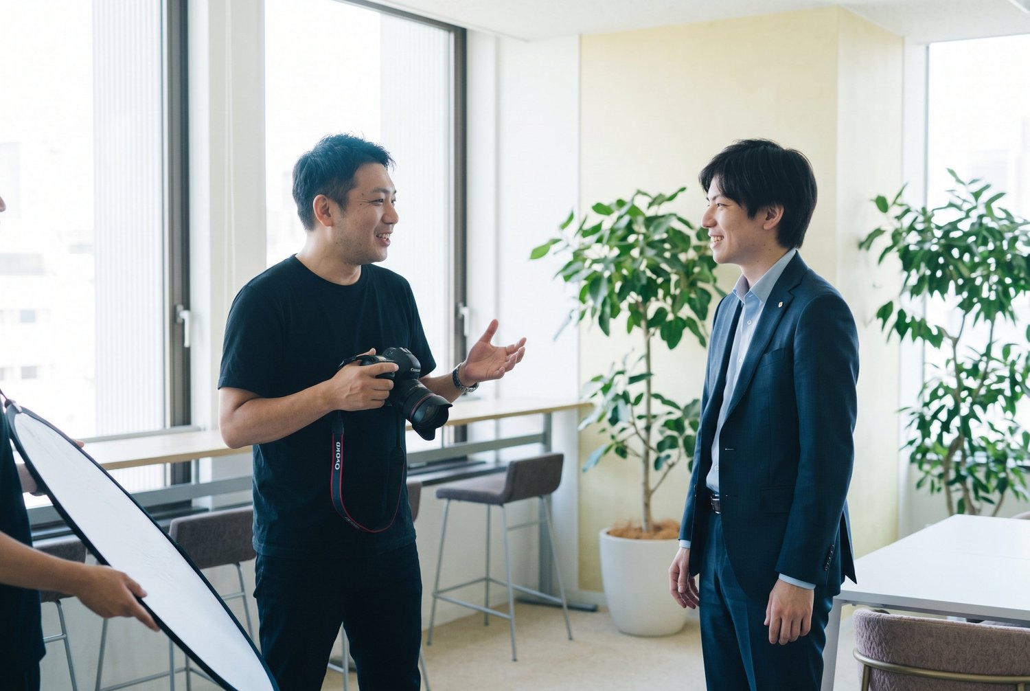 撮影の合間に会話をしながら、自然な表情を引き出すカメラマンと被写体の男性