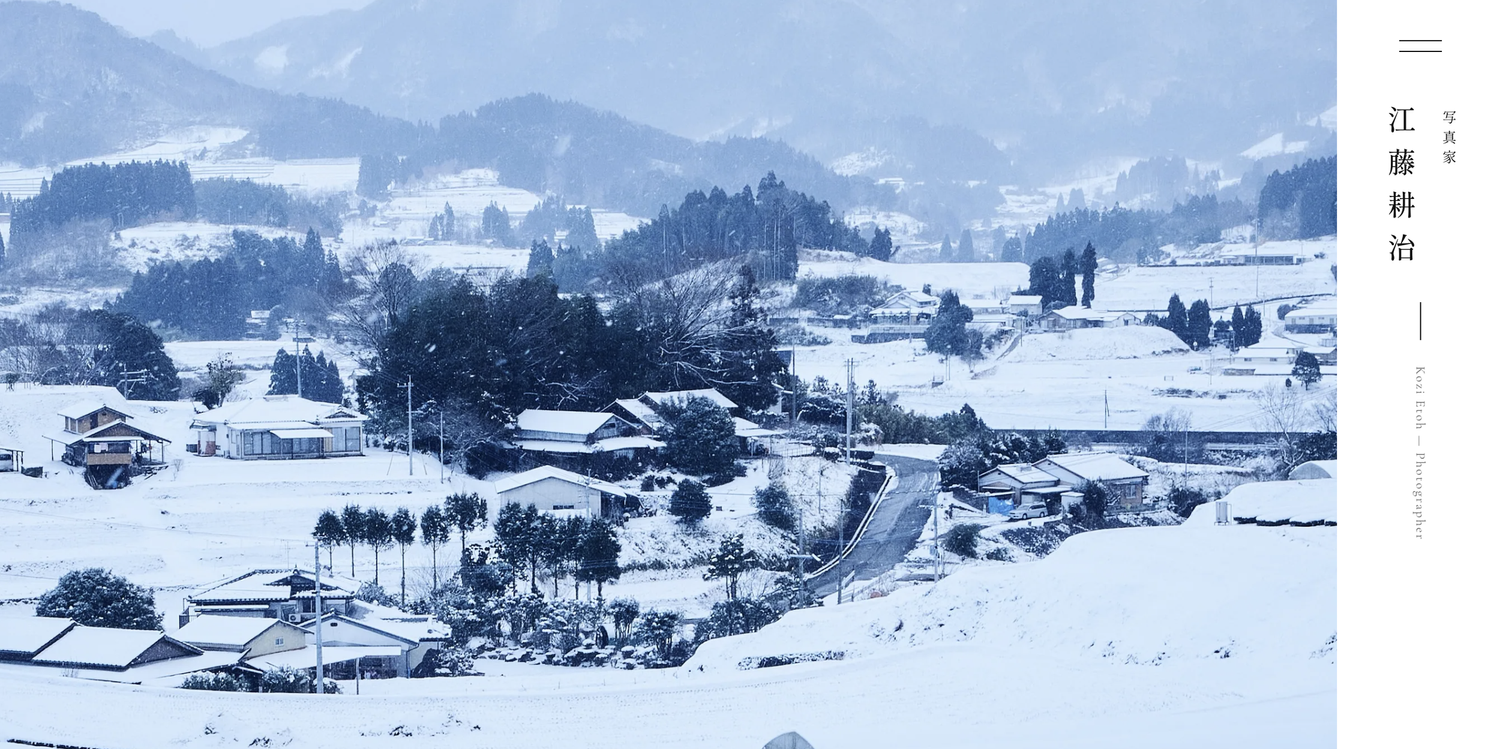 写真家・江藤耕治の個人サイト kozi-etoh.com のトップページ。雪に包まれた山あいの集落の写真と縦書きの名前